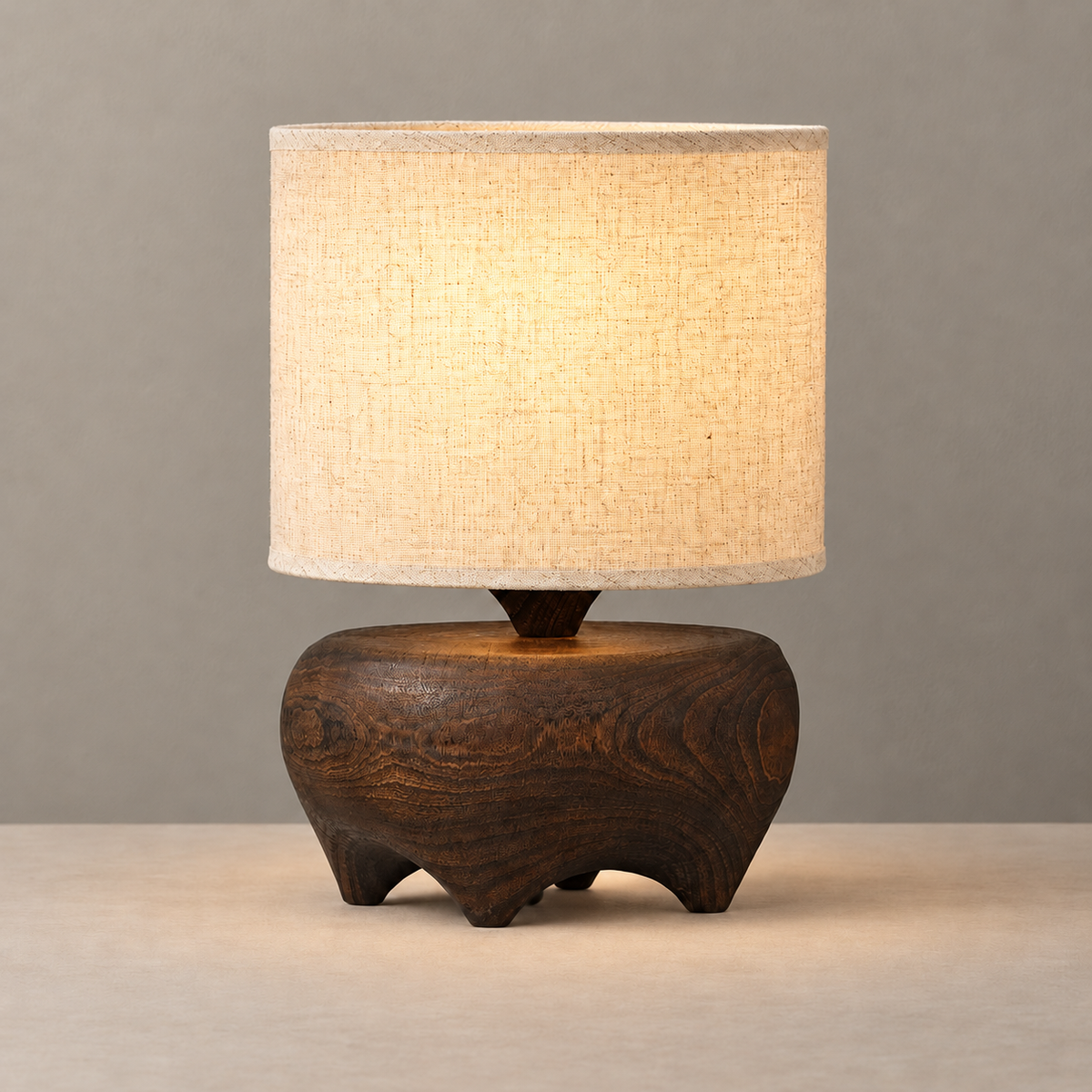 Carved wood table lamp with its linen shade illuminated