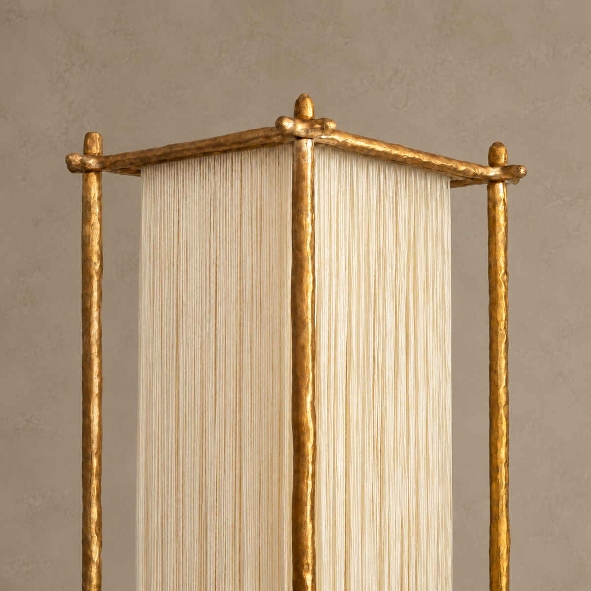 Close view of Cascade's hammered brass top rails and the ivory silk strands suspended beneath them.