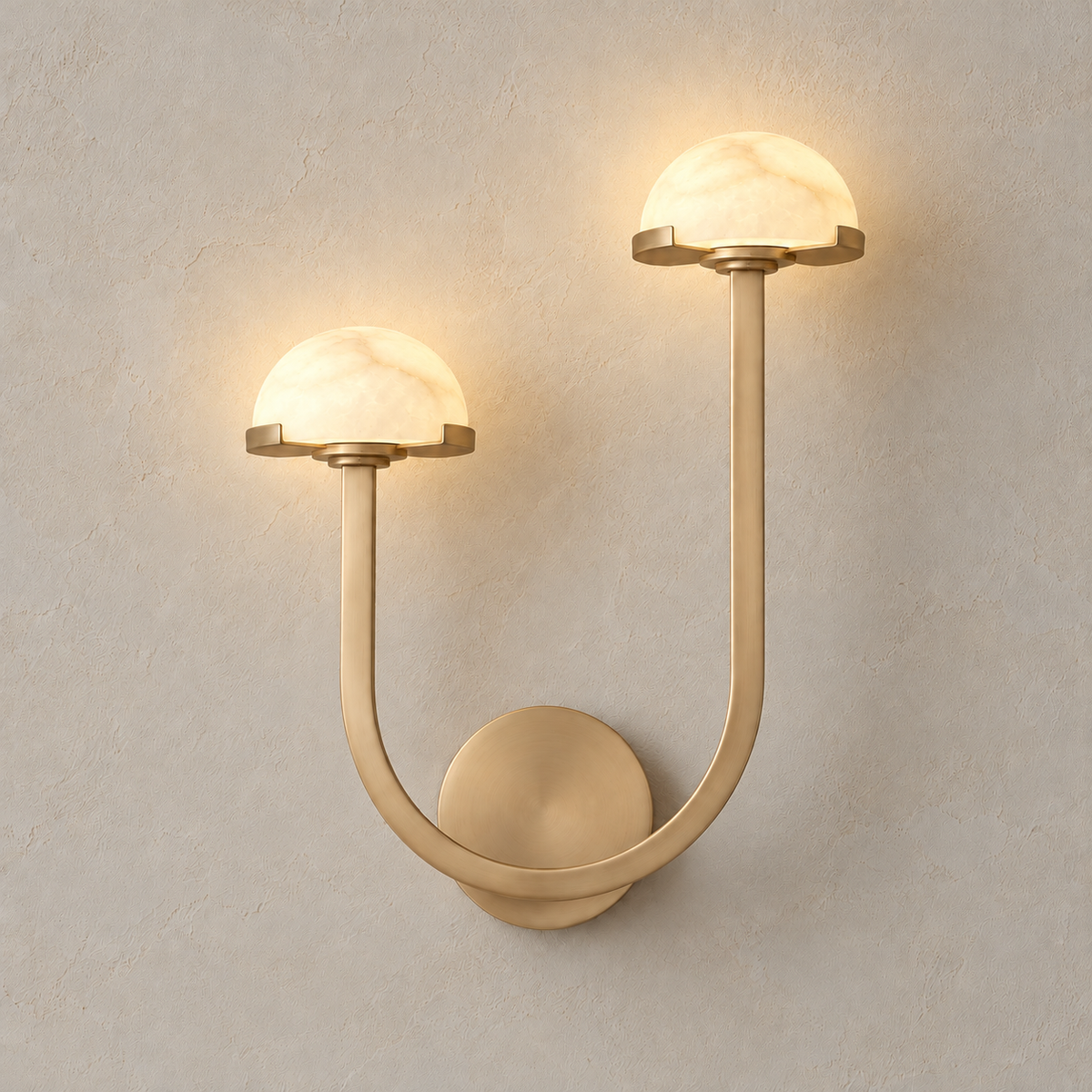 Double alabaster dome wall sconce illuminated, with the taller brass arm on the right.
