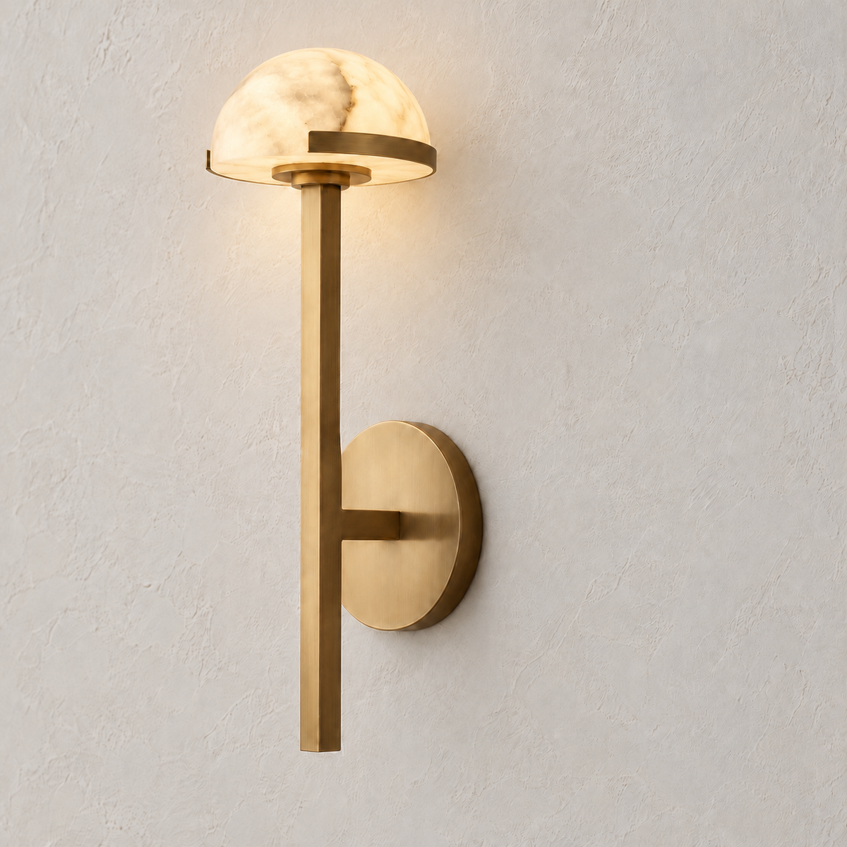 Brass and alabaster dome wall sconce, illuminated on ivory plaster.