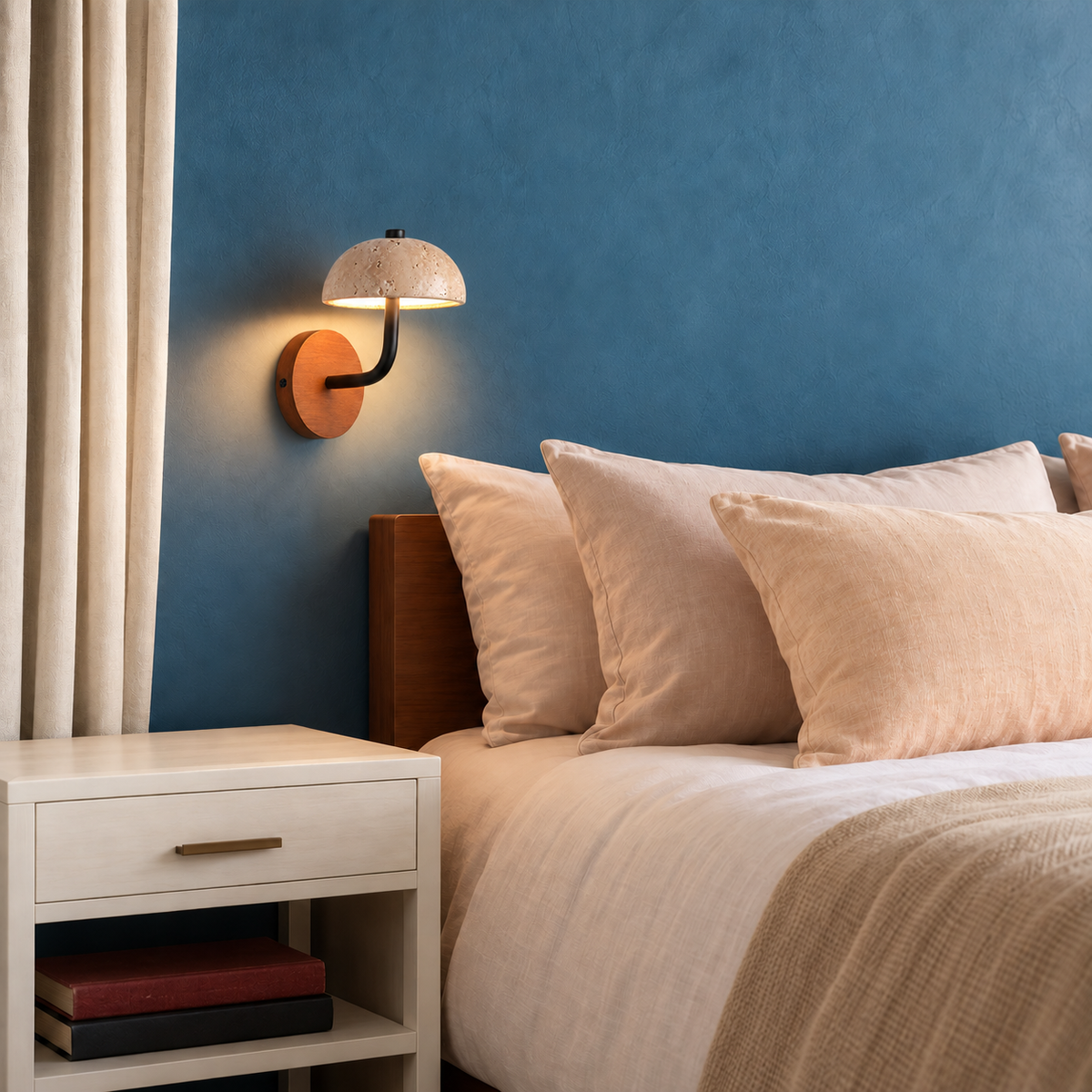 Travertine dome wall light mounted beside a bed in a blue bedroom.