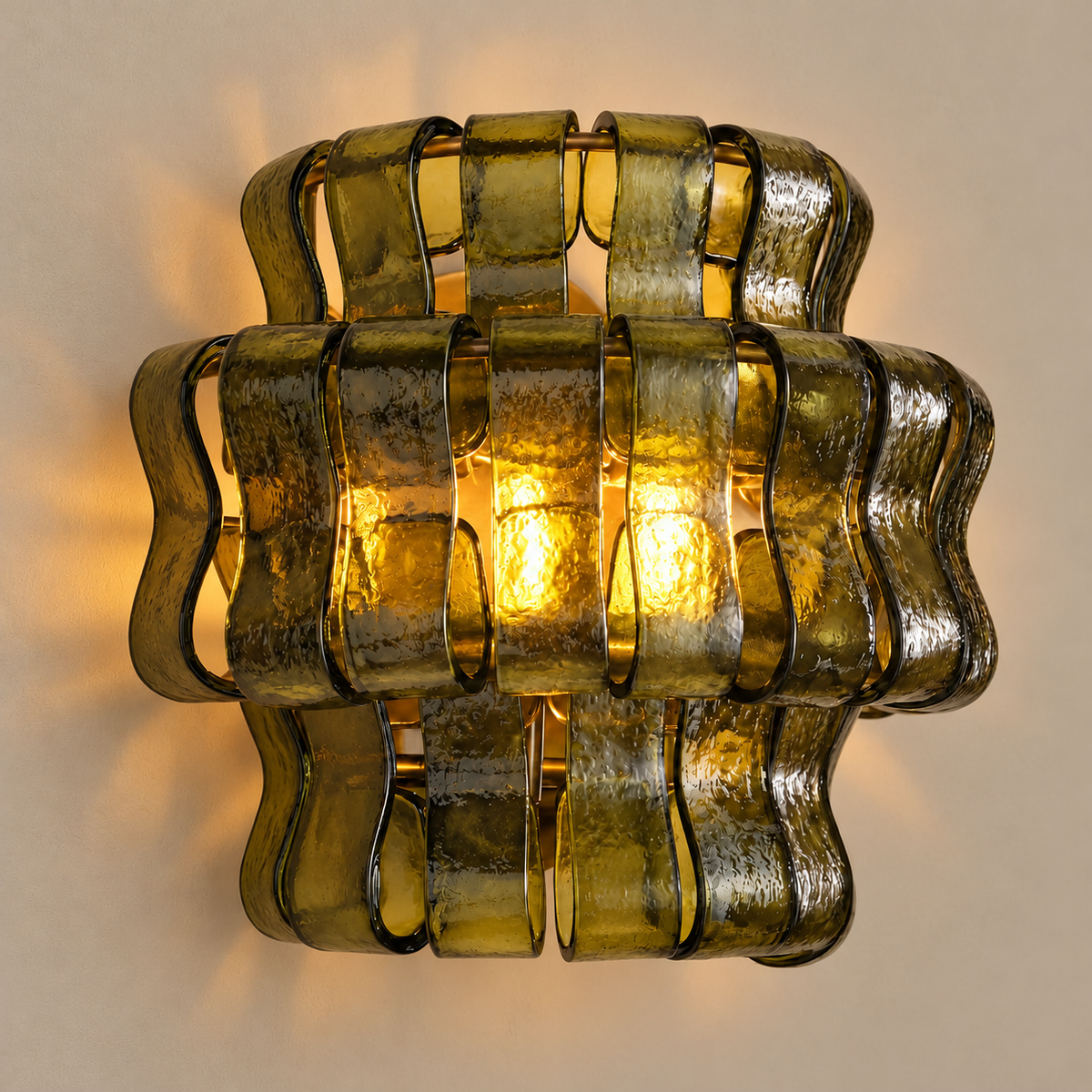 Bellatrix green glass wall sconce, illuminated on a stone-beige wall
