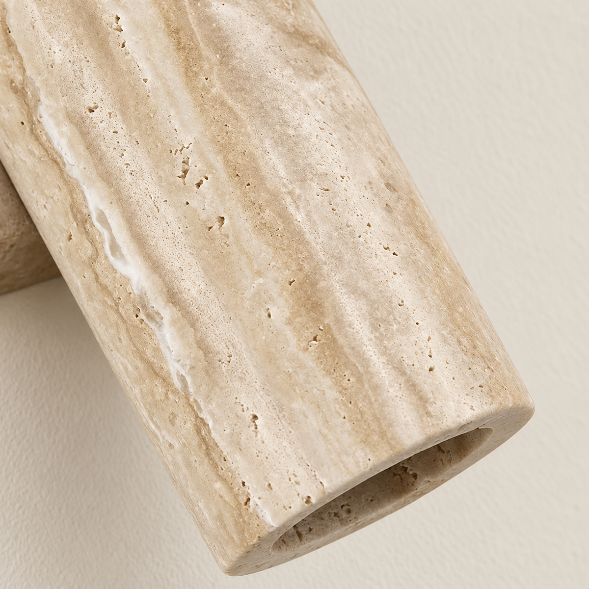 Close-up of the travertine cylinder’s porous stone surface and recessed lower opening.