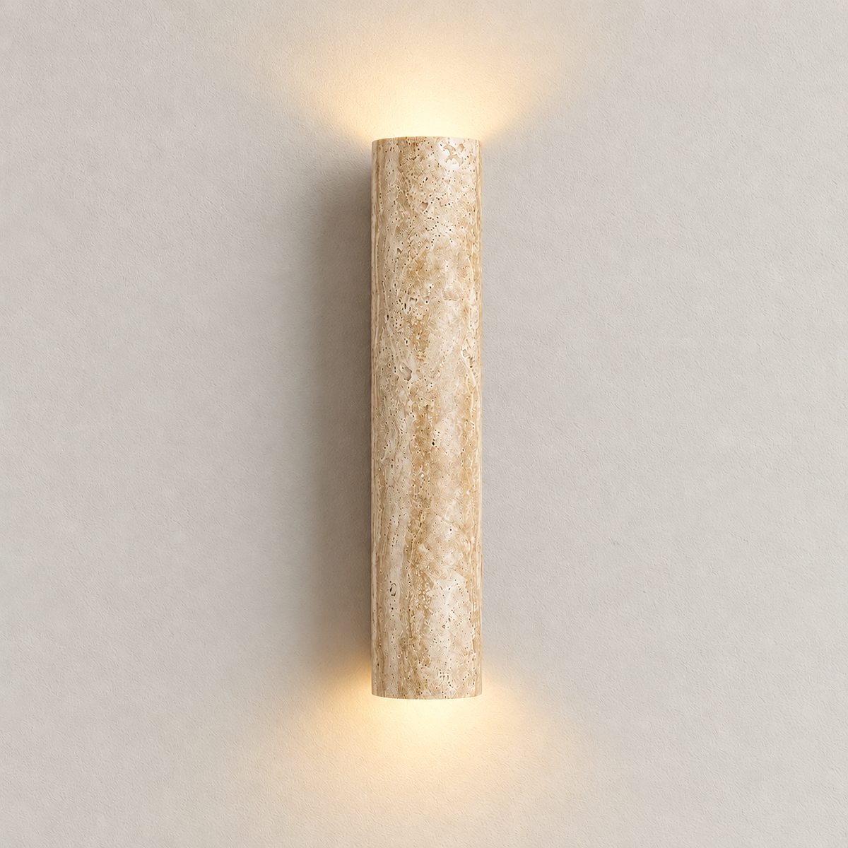 Front view of the illuminated travertine cylinder wall sconce on warm ivory.