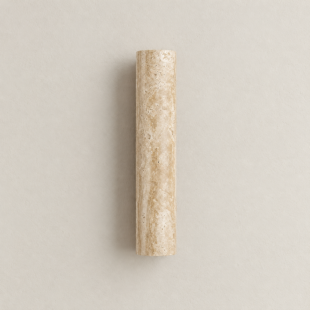Front view of the unlit travertine cylinder wall sconce on warm ivory.