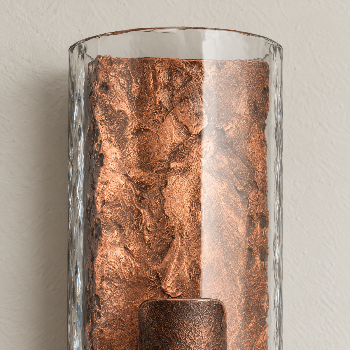 Close-up of the clear glass edge and textured copper-finish steel core of the wall sconce.