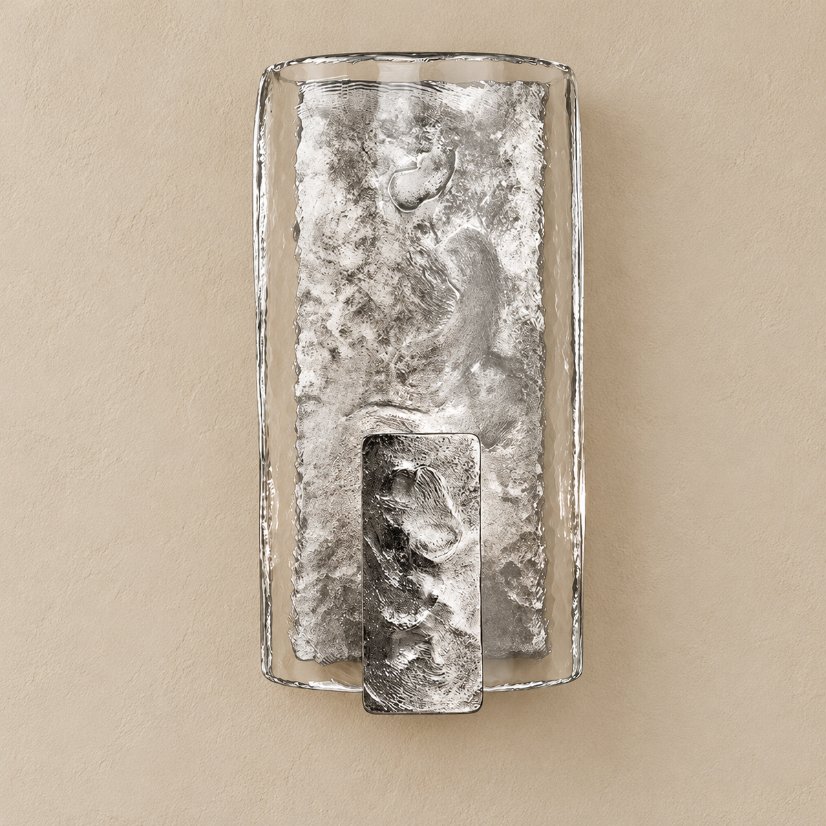 Front view of the silver-finish glass wall sconce with a hammered metal core and lower shield on beige.