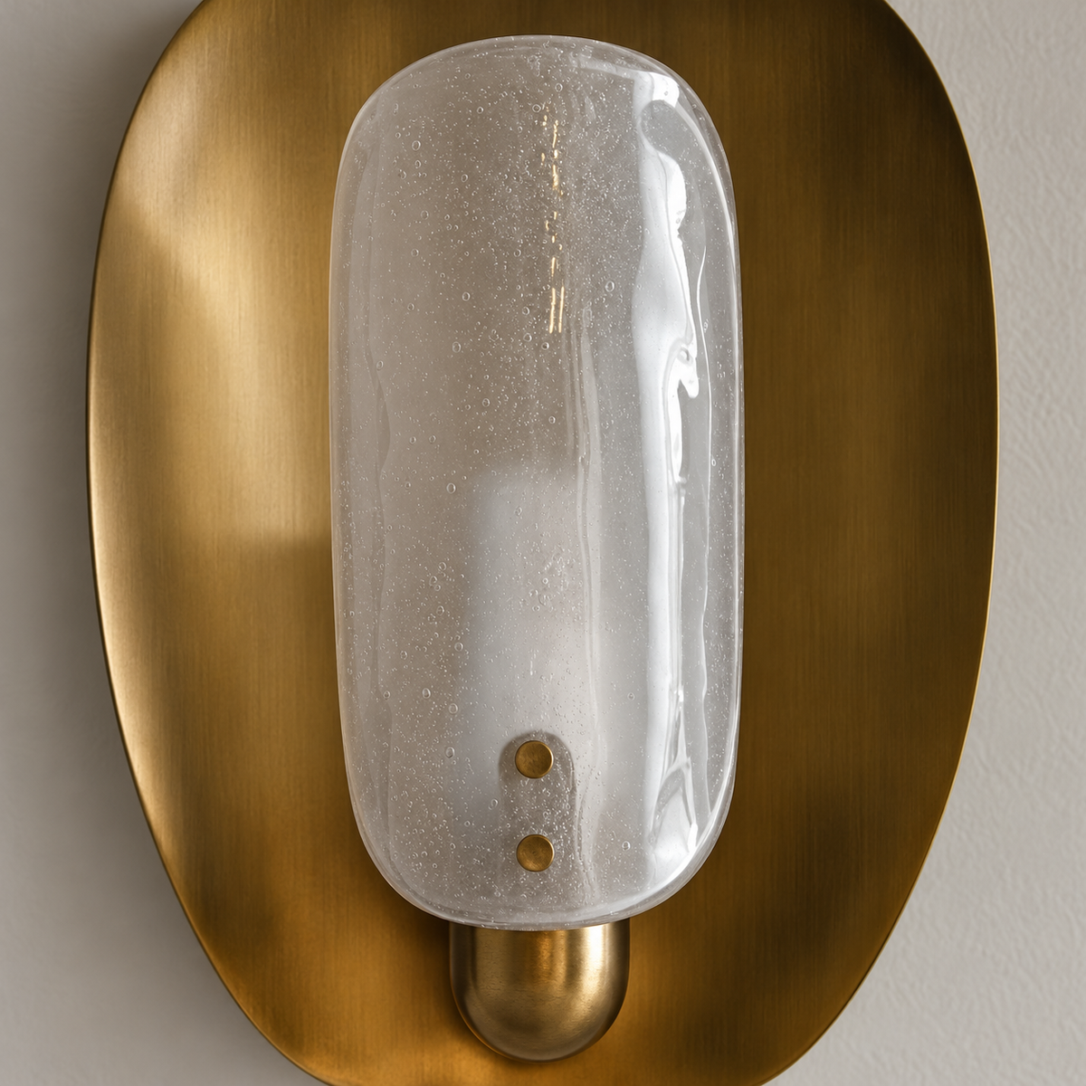 Close-up of the convex bubbled glass shade and two brass retaining pins on the wall sconce.