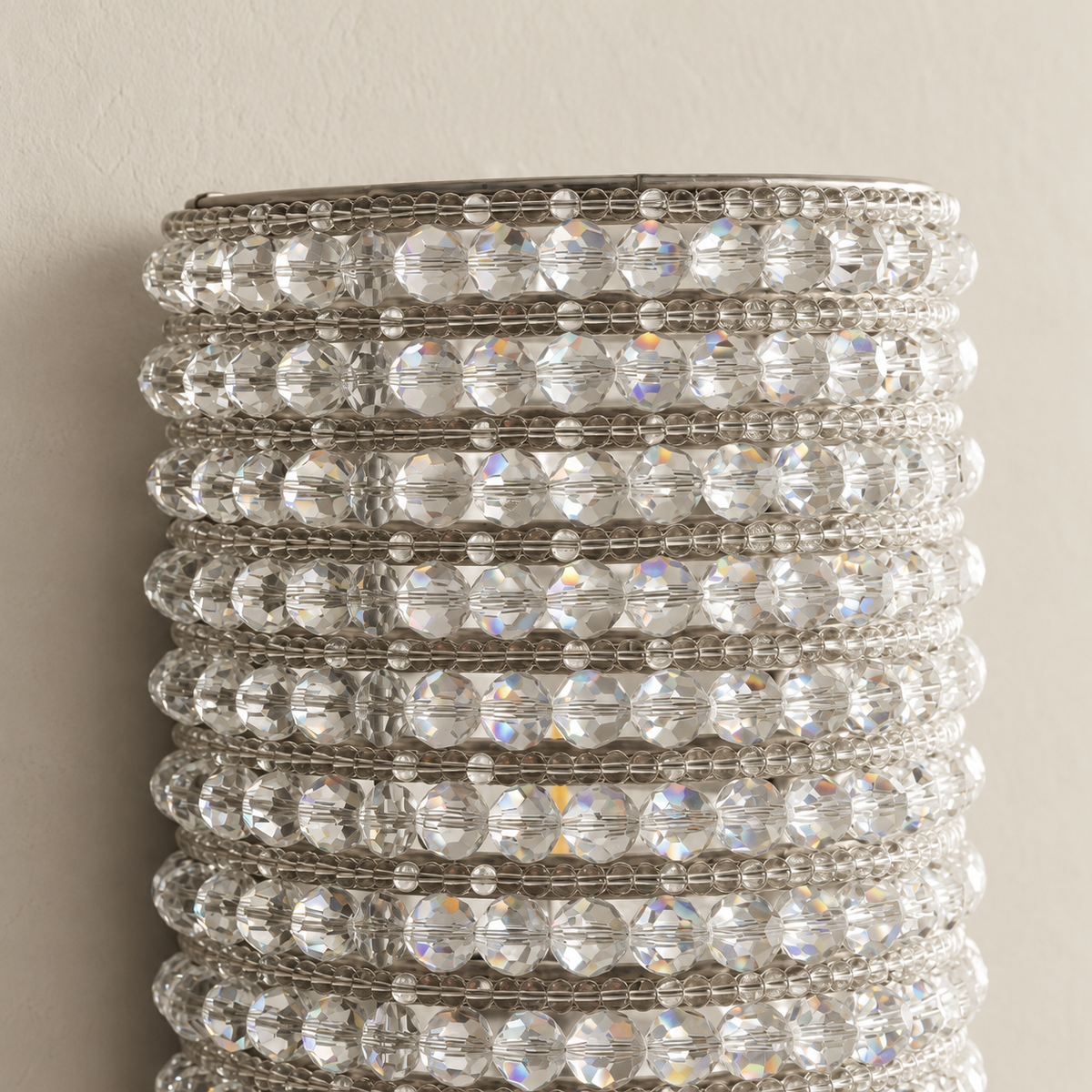 Close-up of faceted clear crystals and silver frame at the top of the wall sconce.