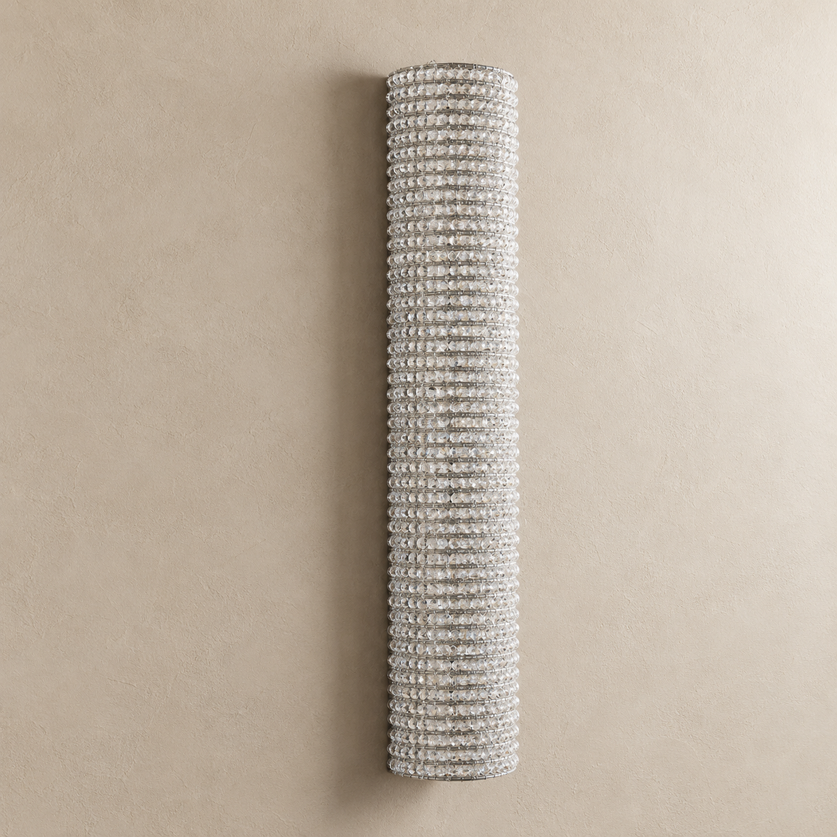 Tall 90 cm clear crystal wall sconce with silver frame on beige plaster.