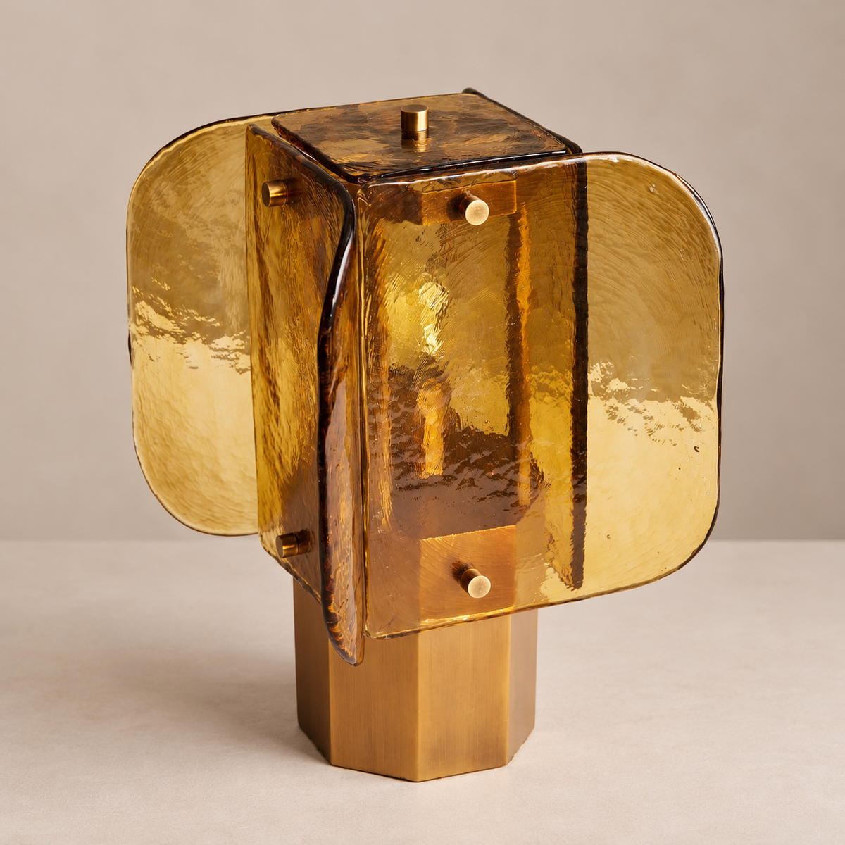 Amber glass table lamp with layered panels and a faceted metal base, unlit