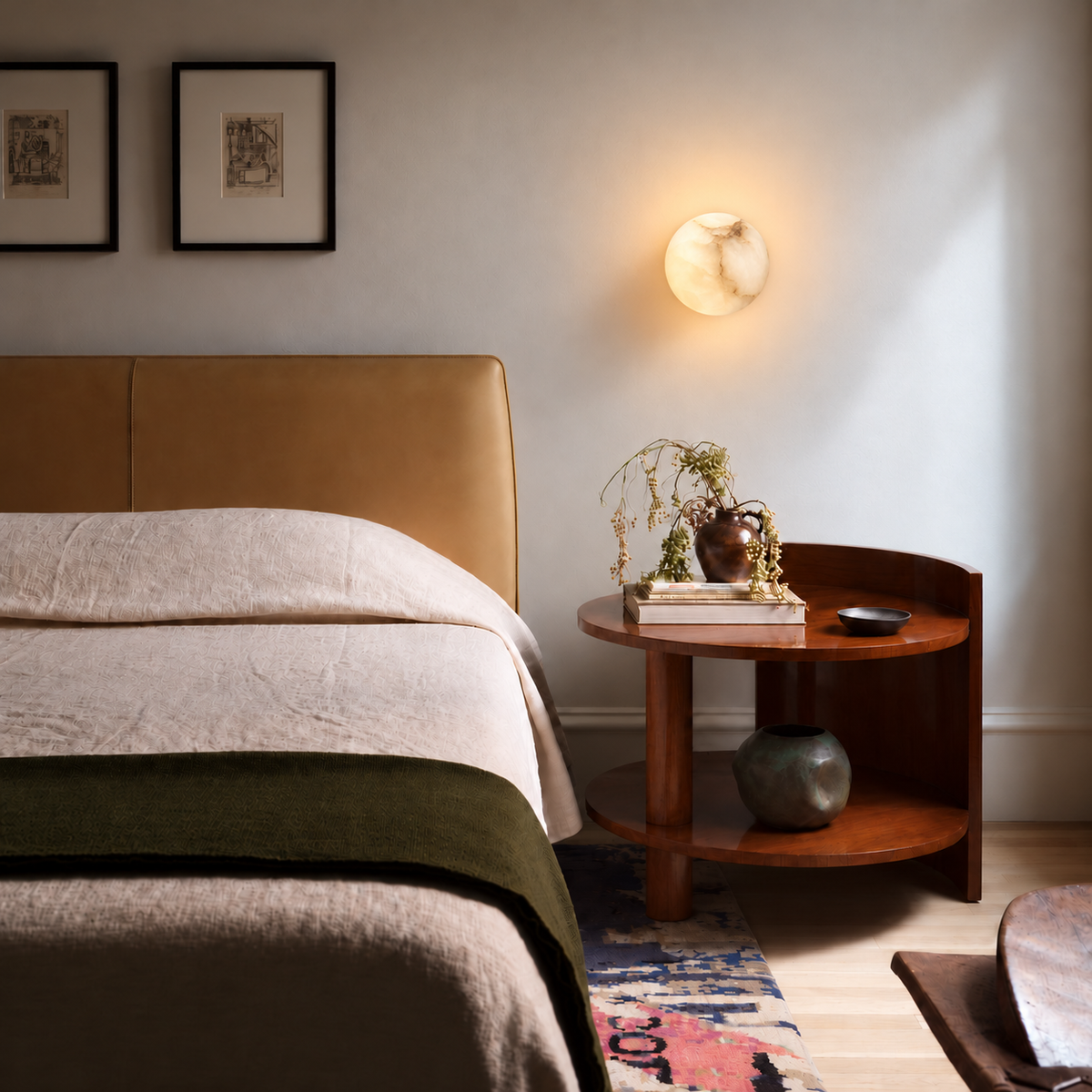 Front view of an illuminated 15 cm alabaster globe wall sconce mounted above a walnut bedside table.