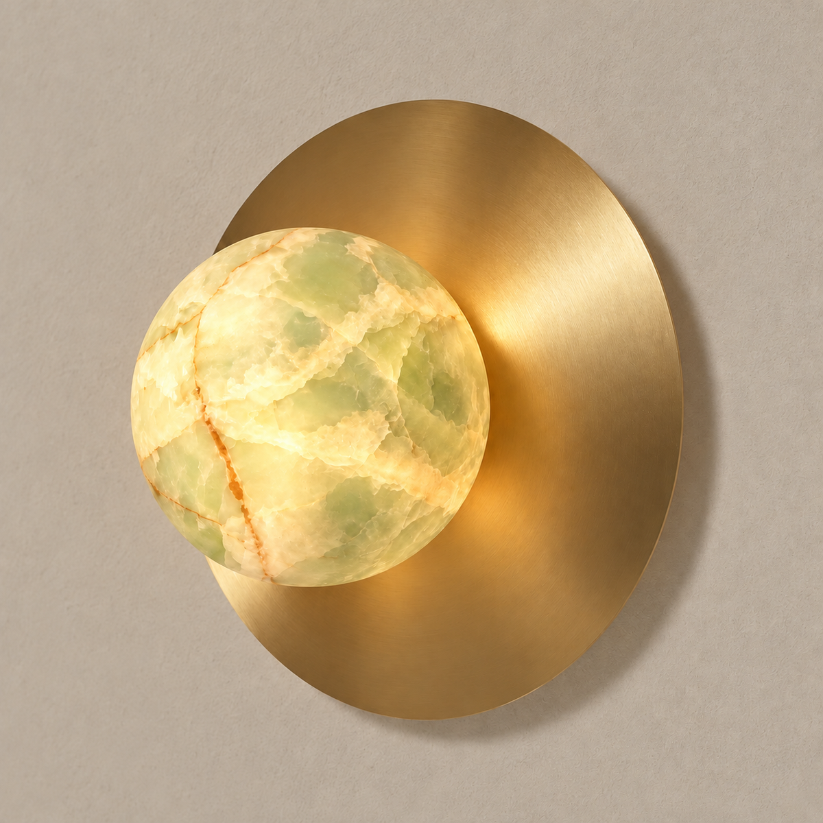 Green onyx globe sconce illuminated against its brass disc.