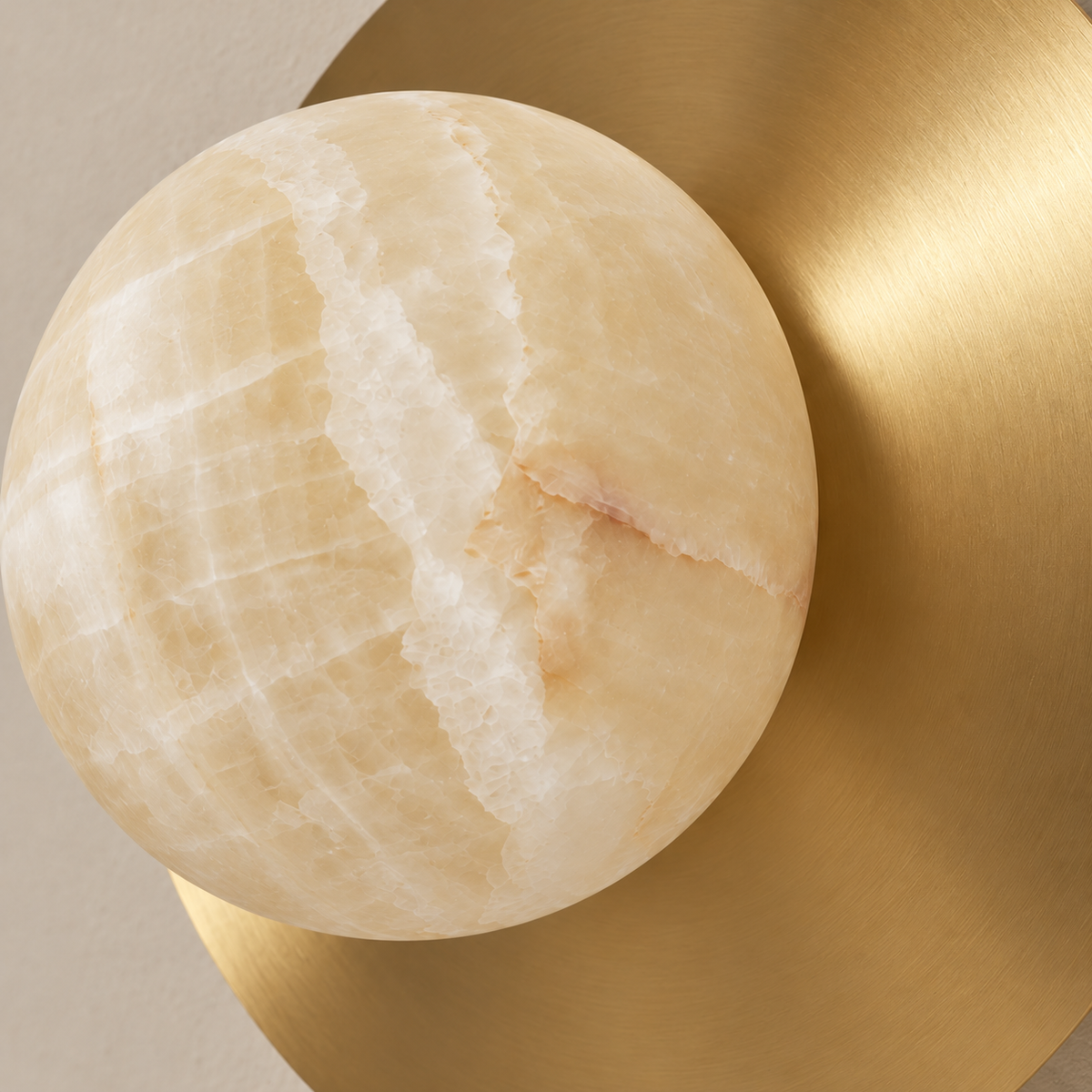 Close detail of honey onyx mineral bands beside the brushed brass disc.