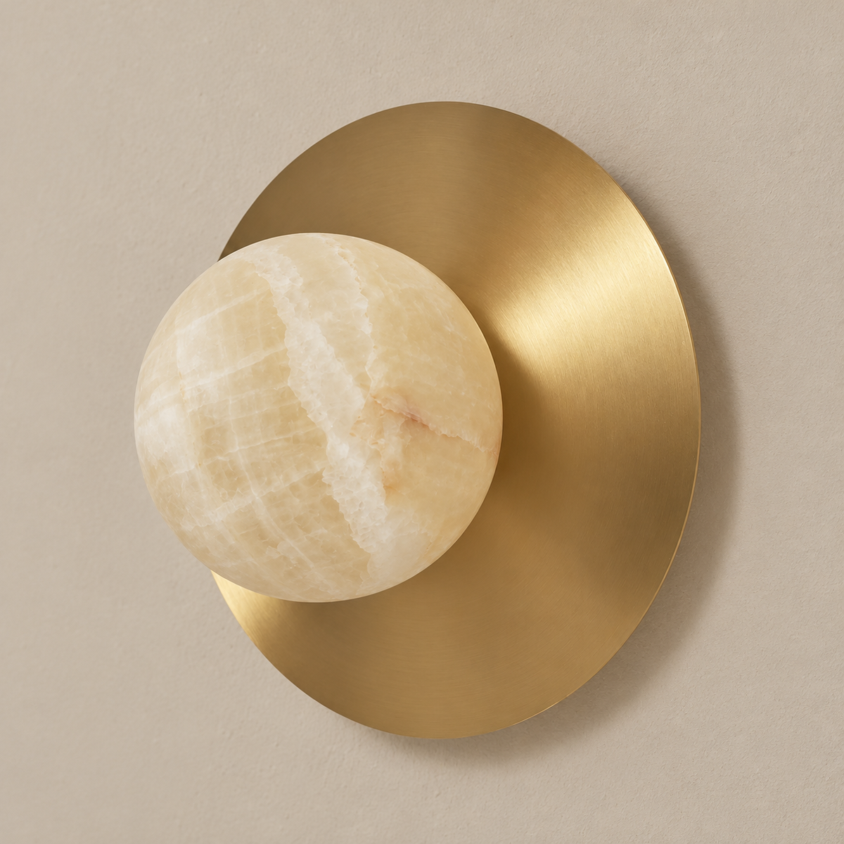 Honey onyx globe on a brushed brass disc, shown unlit on the wall.