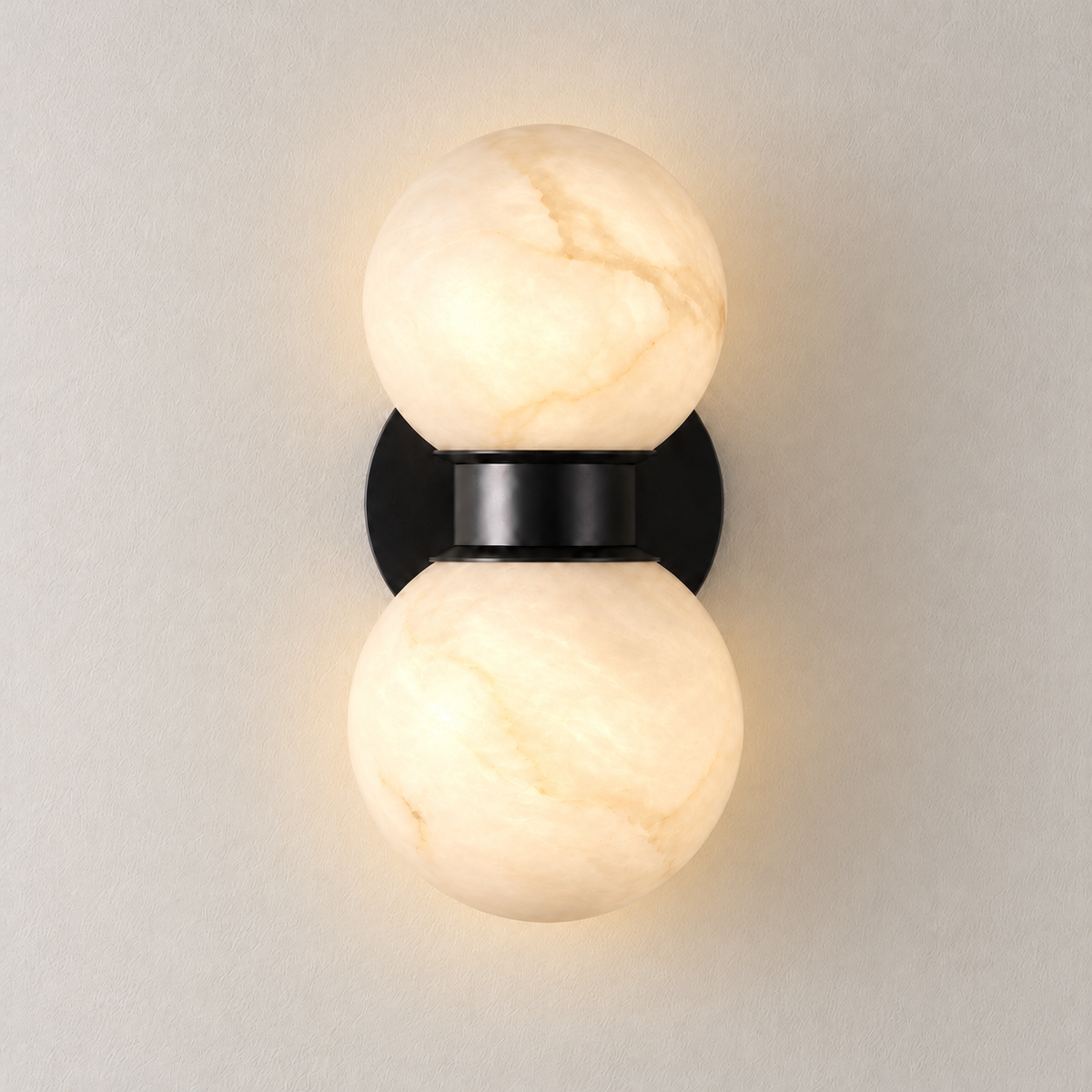 Double alabaster globe sconce illuminated on an ivory wall, front view.
