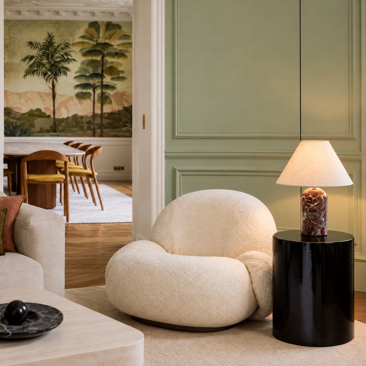 Red marble table lamp beside a cream armchair in a sage living room.