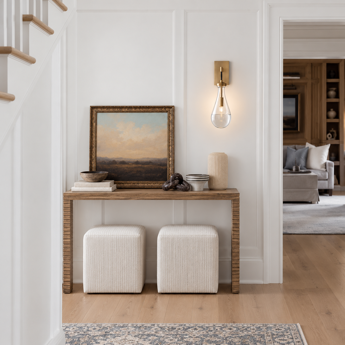 Raindrop brass and glass wall sconce installed above a console in a bright entryway.