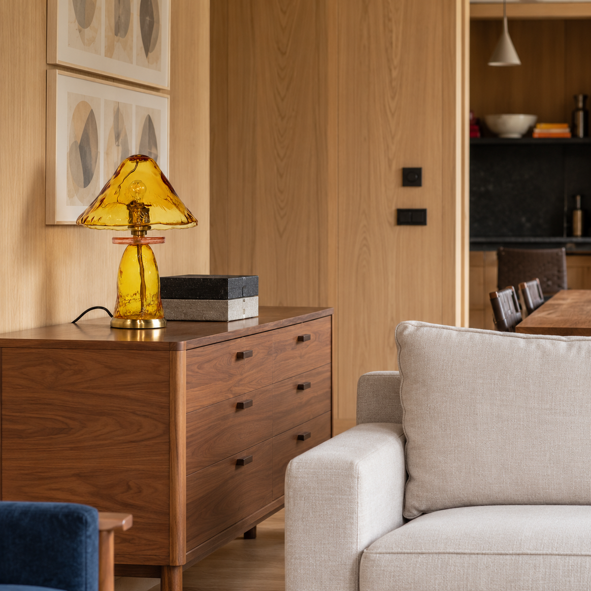 Amber glass table lamp with a pink glass collar and brass fittings, placed in a living room setting