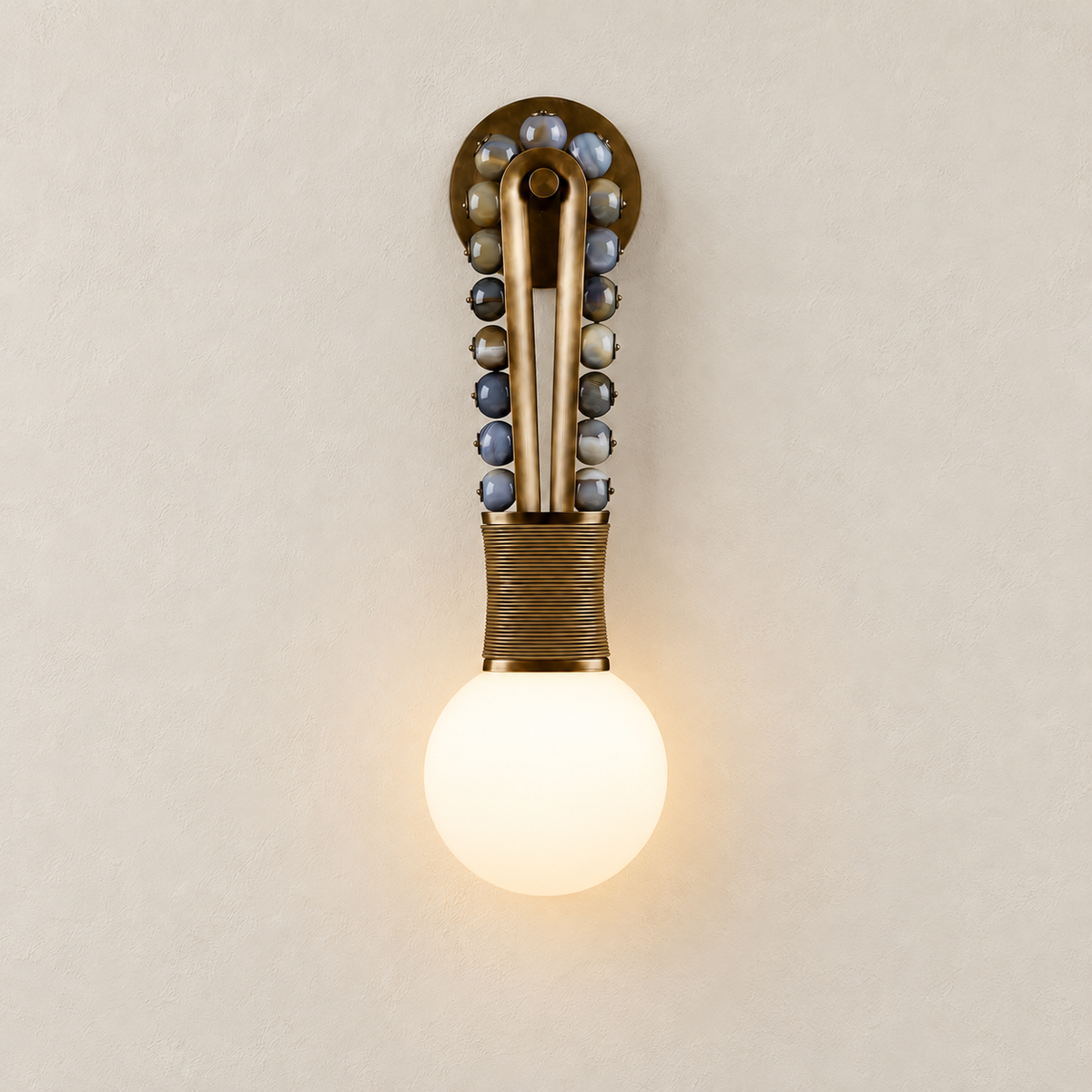 Patinated brass and jade-bead wall sconce with the globe illuminated.