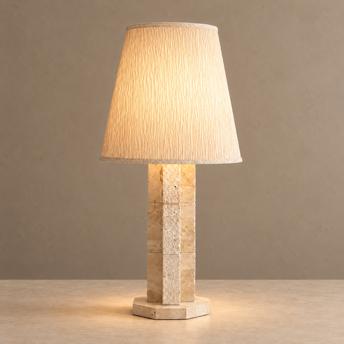 Travertine block lamp with its cream shade illuminated.