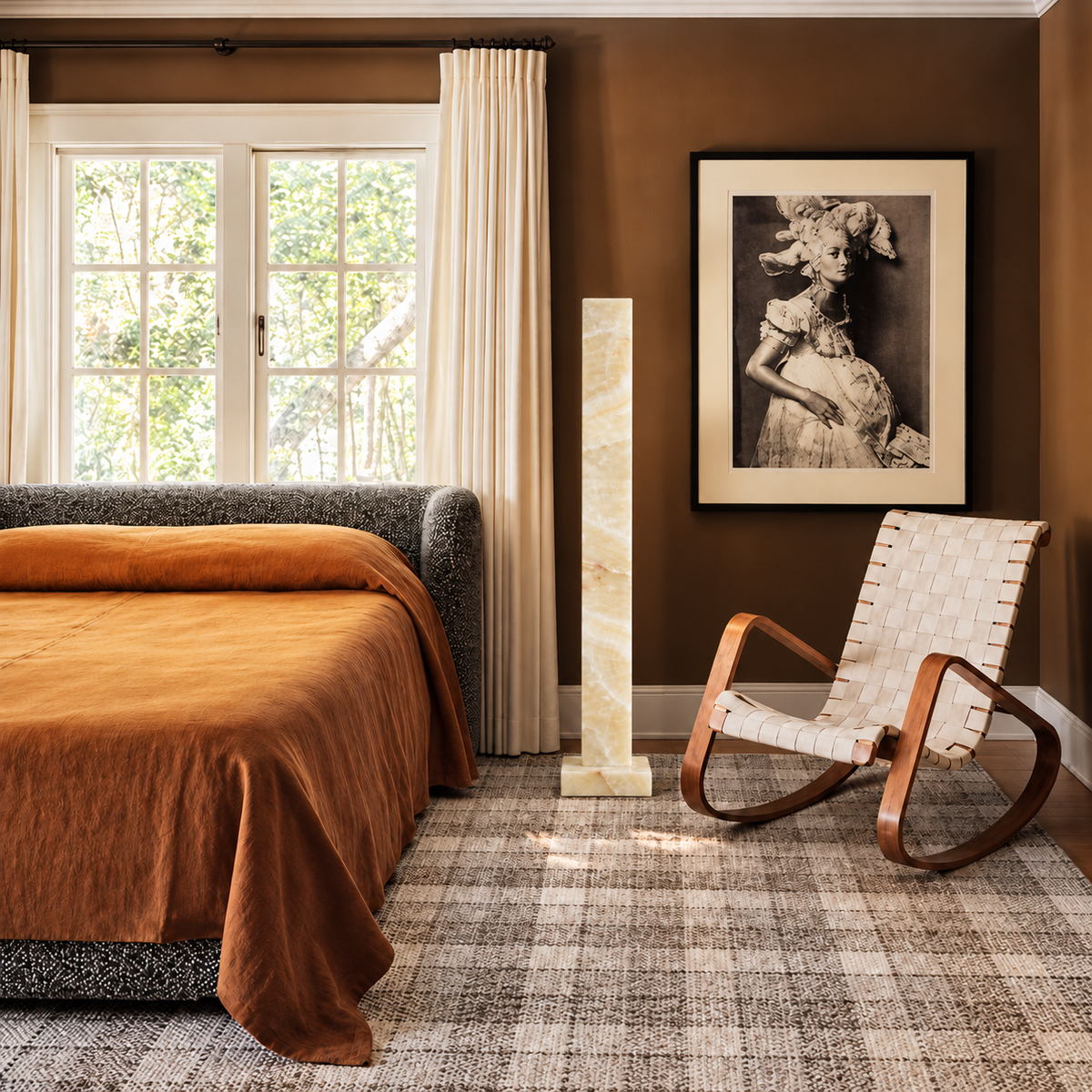 Large honey onyx column floor lamp beside a rocking chair in a brown bedroom.