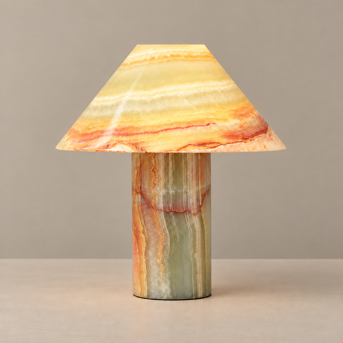 Banded stone table lamp with a conical shade, illuminated on a beige background
