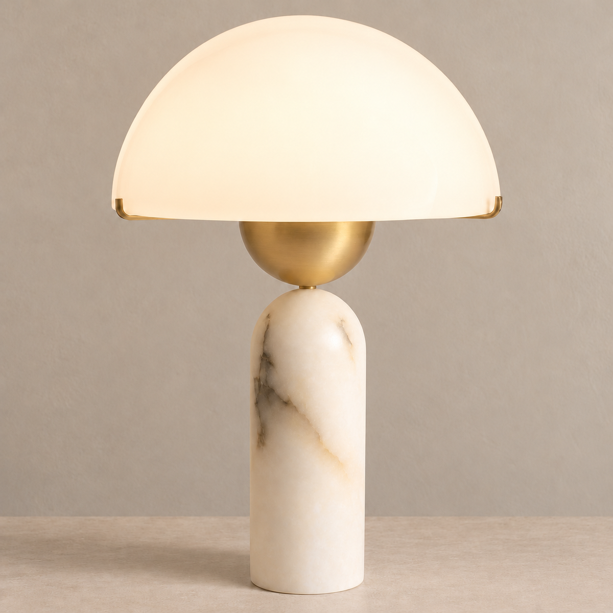 White dome table lamp with a marble column and brass bowl, illuminated on a beige background