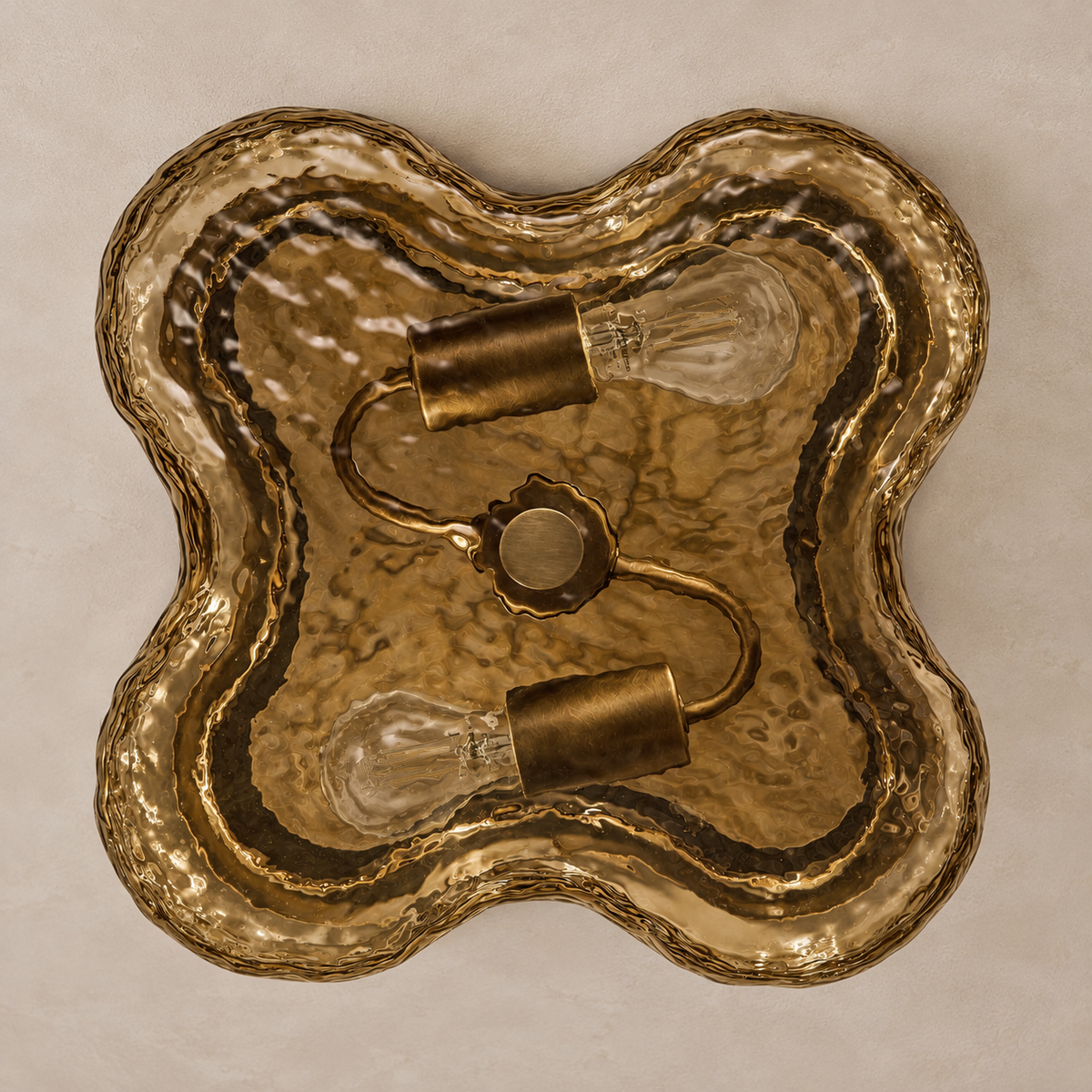Underside of the four-lobed amber glass shade with two unlit bulbs and a central brass retaining cap.