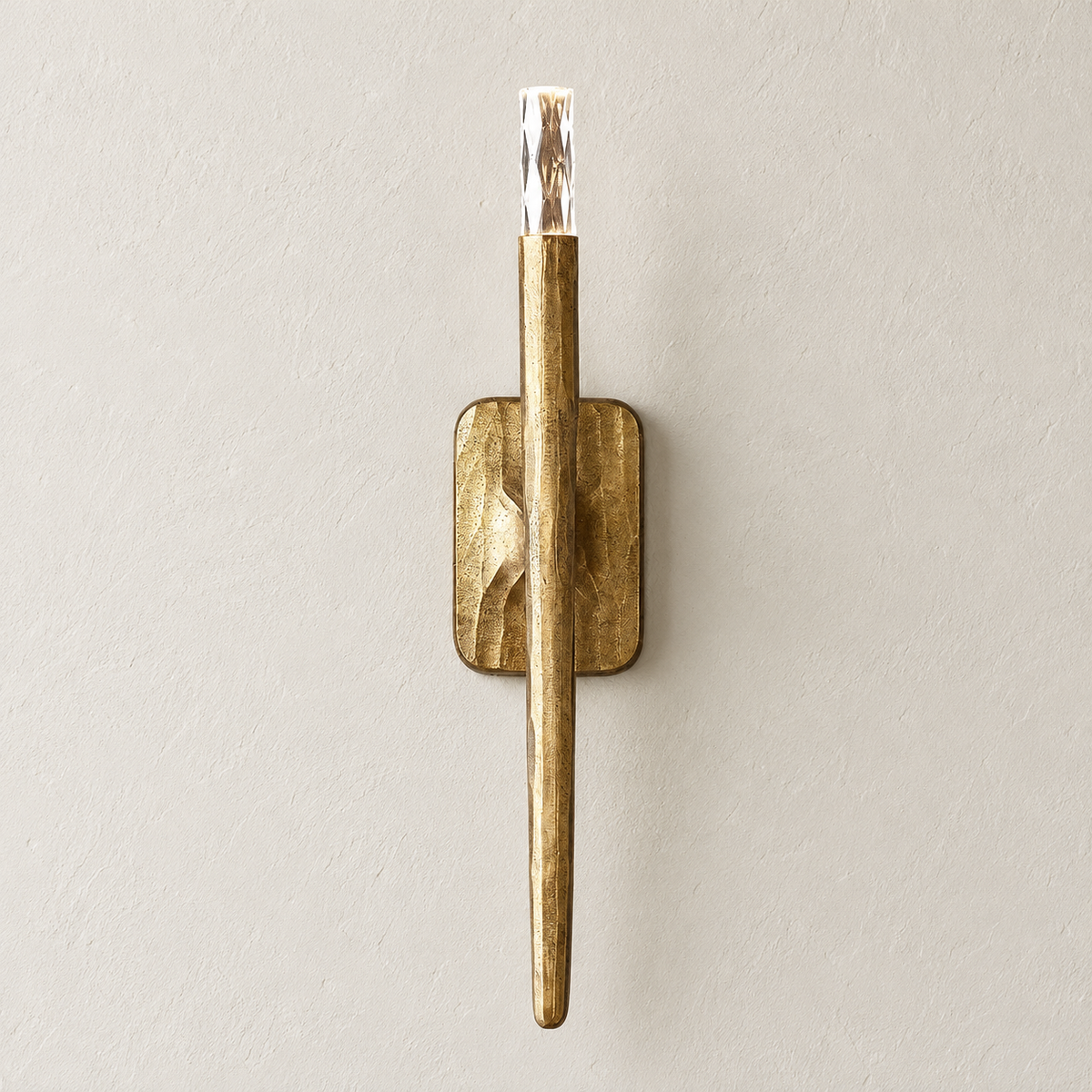 Front view of the sculptural brass wall sconce with a clear crystal tip, switched off.