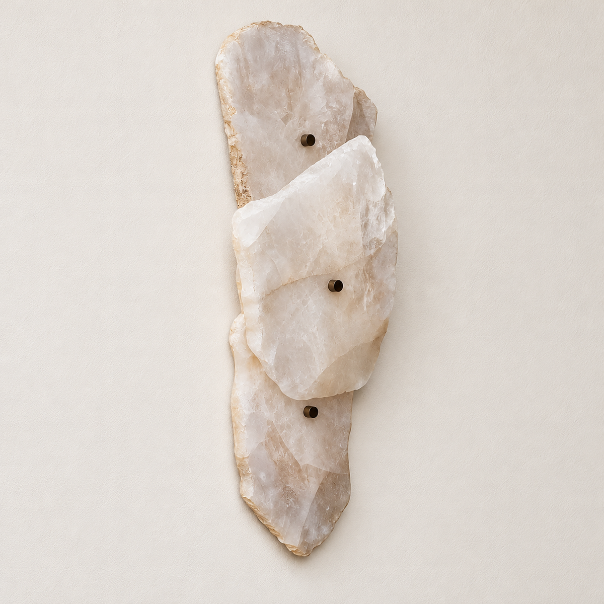 Raw stone wall sconce with three overlapping panels and dark fixing pins unlit against ivory plaster.