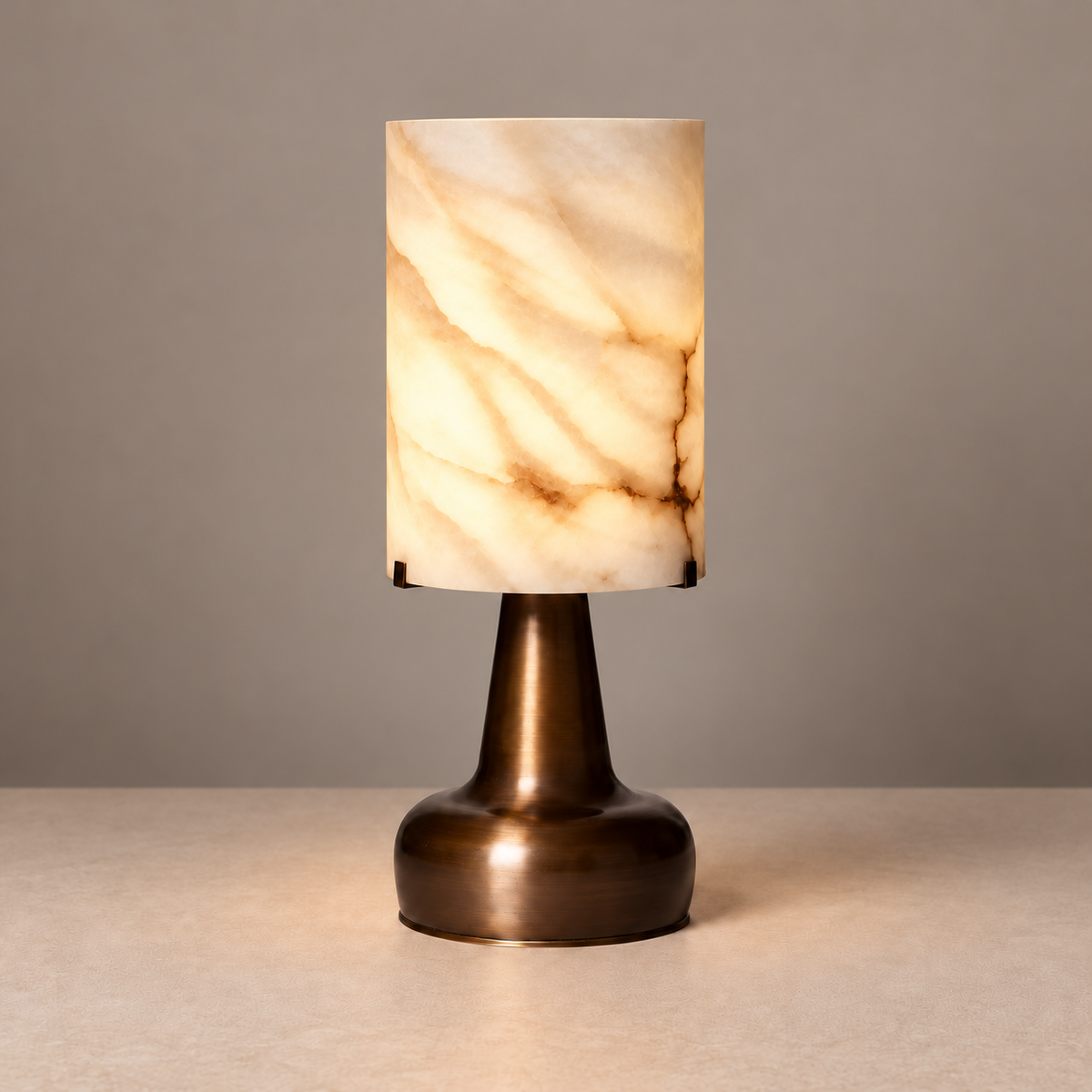 Alabaster cylinder table lamp illuminated, showing natural mineral bands.