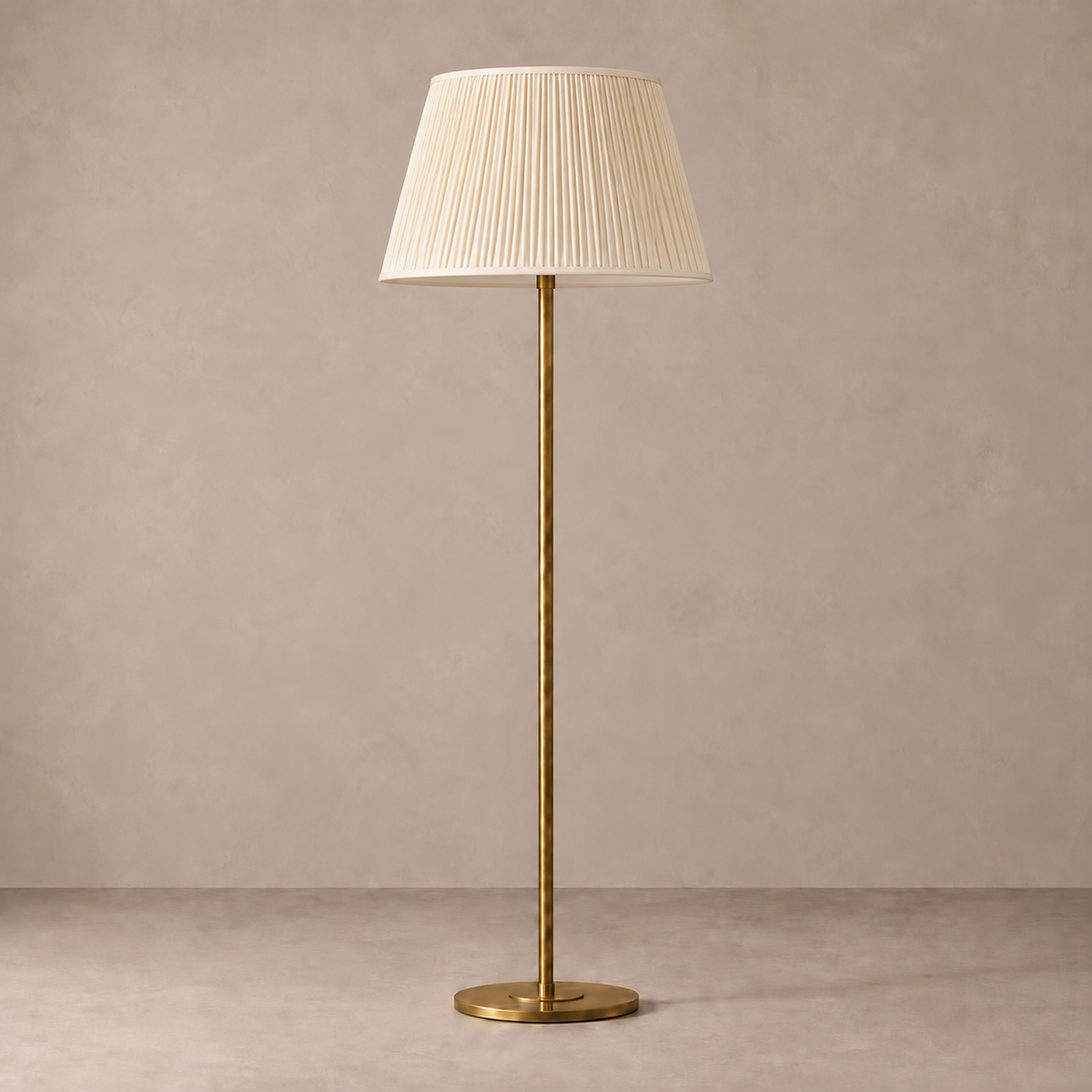 Brushed Brass Floor Lamp with cream fine pleated shade, unlit against a stone-beige background.