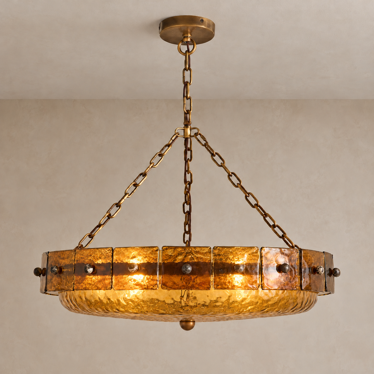 Amber glass bowl chandelier illuminated through its textured panels and shallow glass dish.
