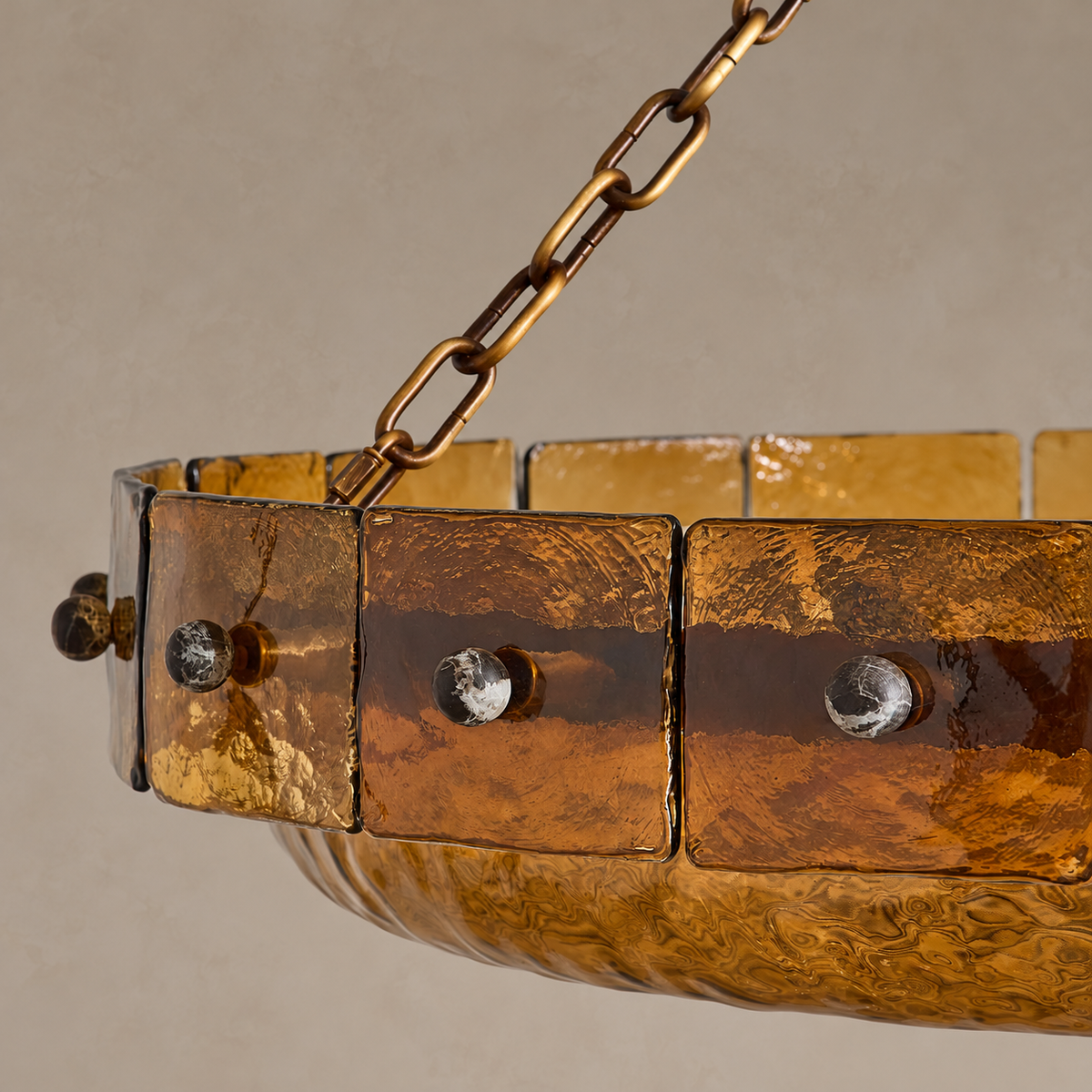 Close view of the rippled amber glass panels, round fasteners and lower glass dish.