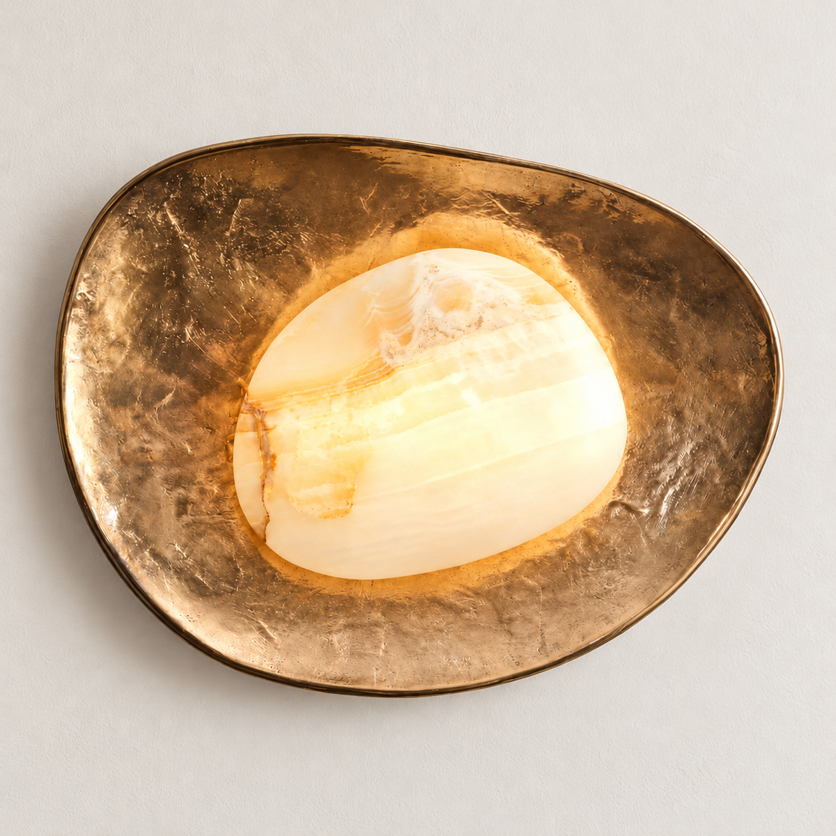 The same marble and brass wall sconce illuminated on ivory plaster.