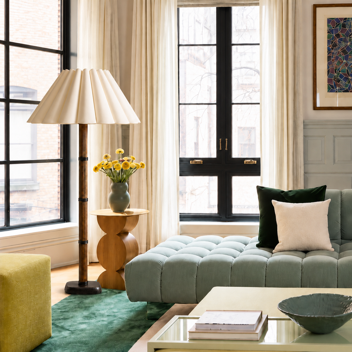 Galerie floor lamp with a broad cream sculptural pleated shade beside a sage sofa in natural daylight.
