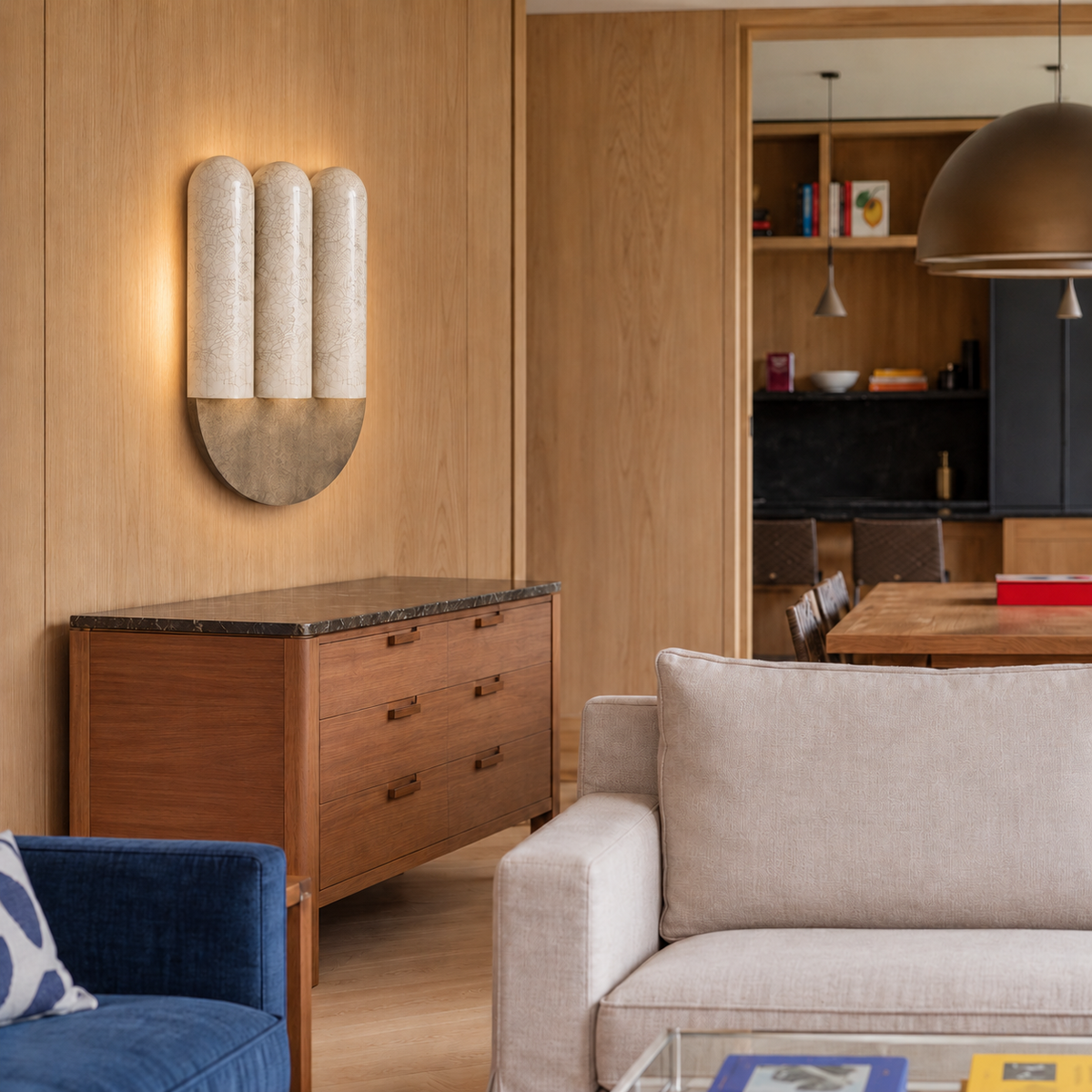 Triple ivory crackle ceramic wall sconce above a chest in a wood-panelled living room.