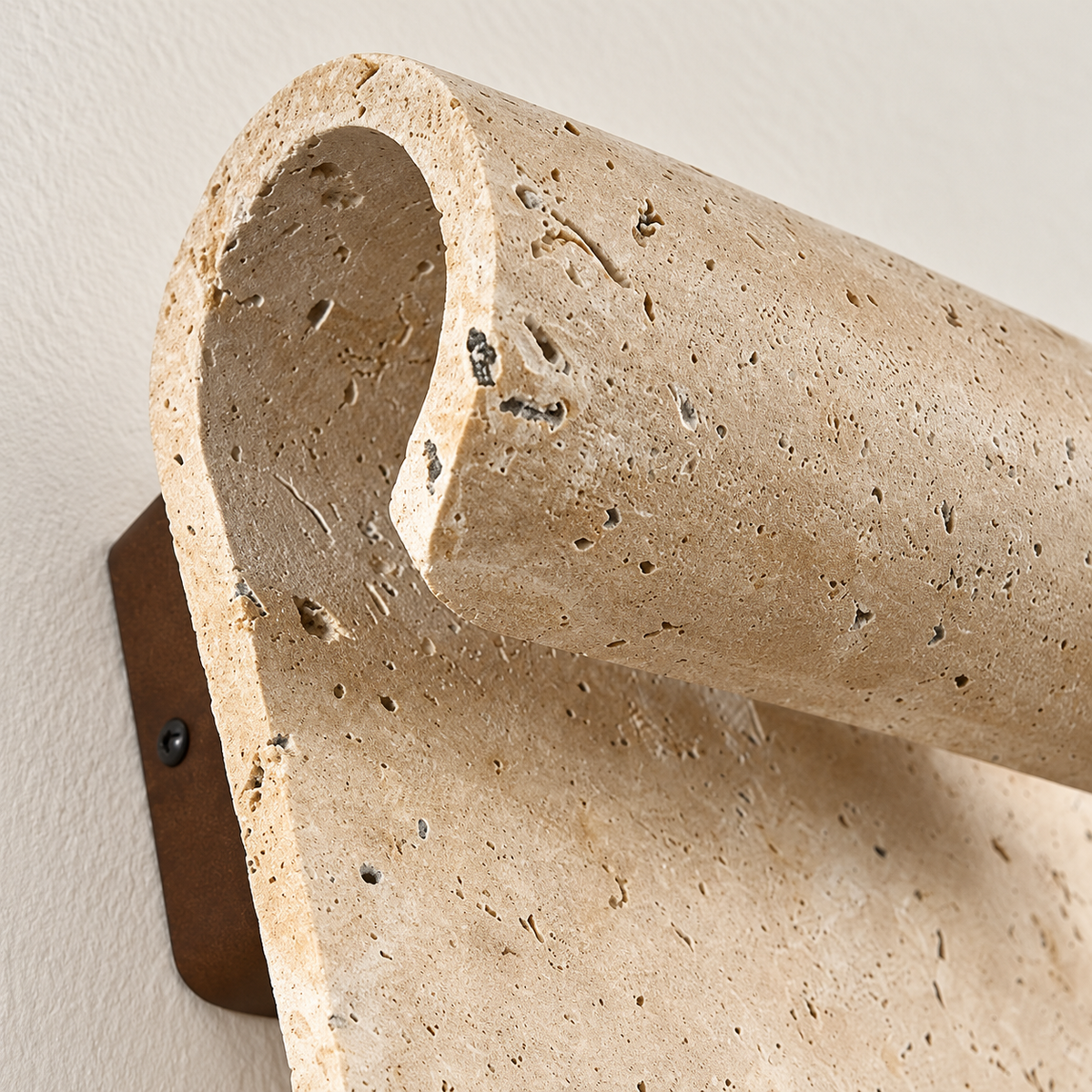 Close-up of curved travertine wall sconce with a rolled upper edge, showing its natural texture.