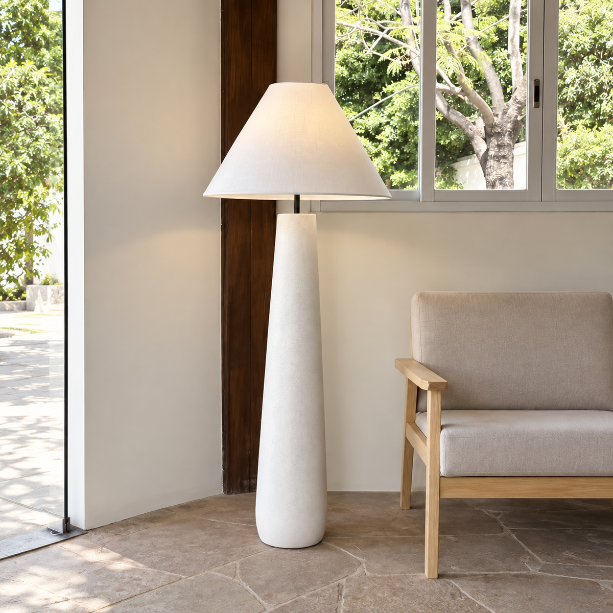 White Fungo Bianco floor lamp beside a wood-framed armchair and large window.