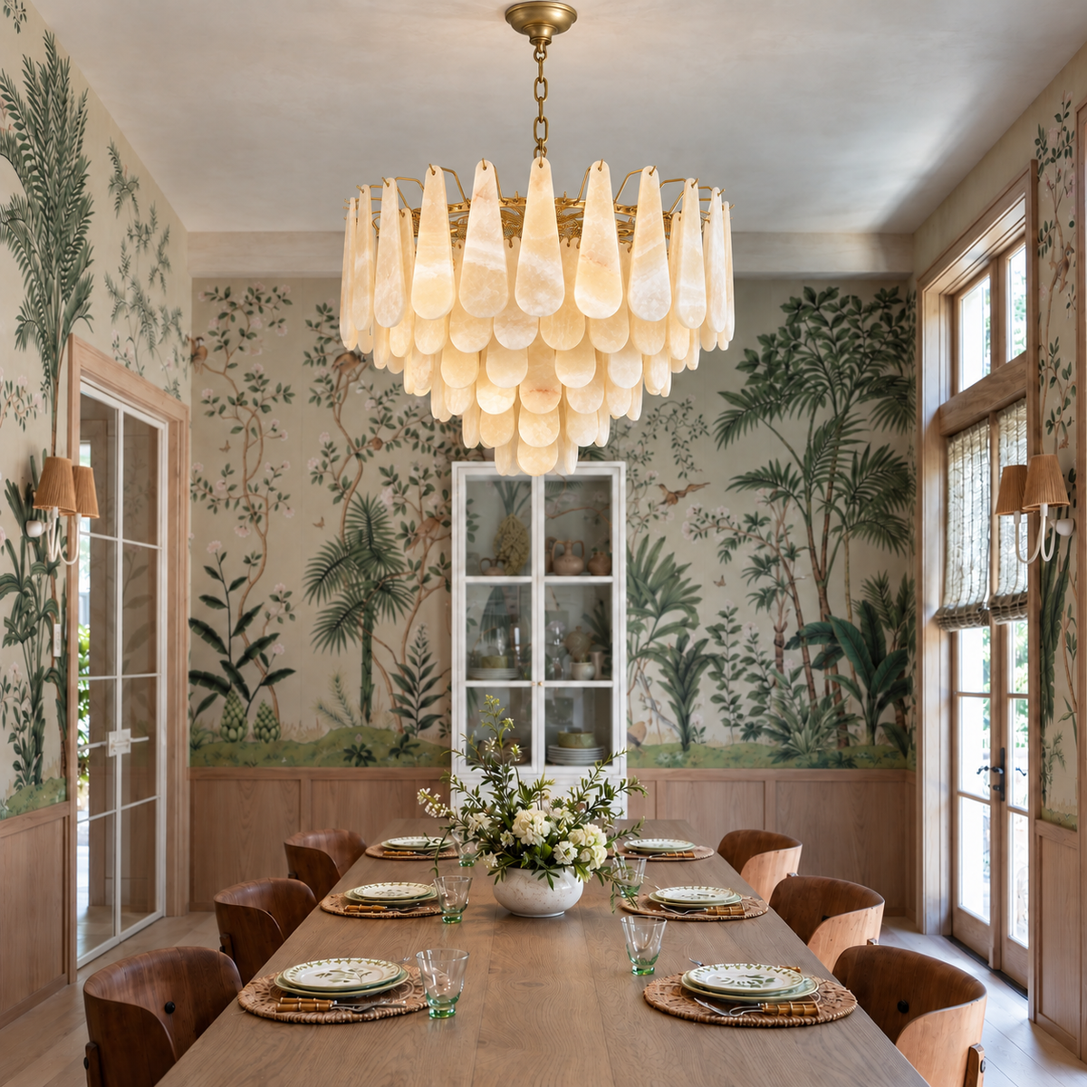 Goccia honey onyx chandelier suspended above a dining table in a botanical dining room.