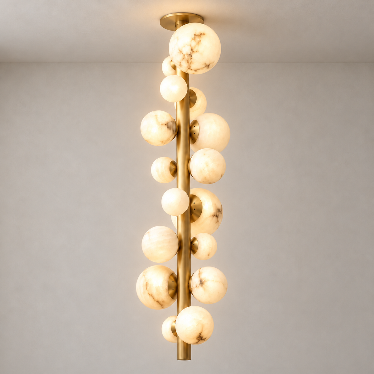 Grappolo chandelier with natural alabaster globes along a brass stem, illuminated.