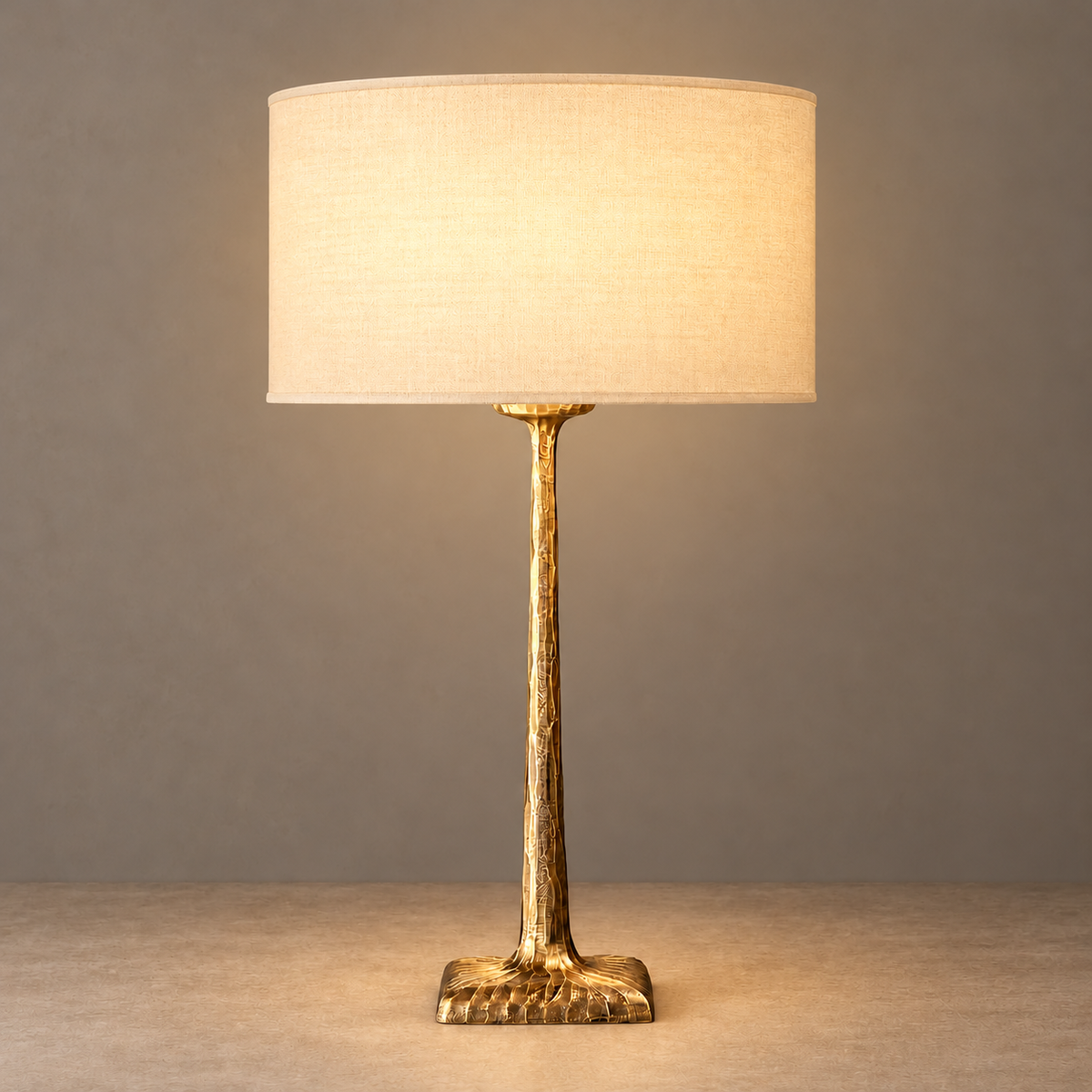 Hammered brass table lamp with its fabric shade illuminated.