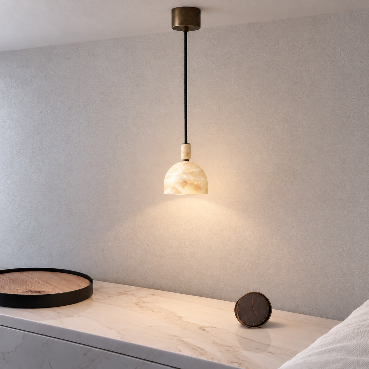 Small honey onyx dome pendant beside a bed, with its cylindrical ceiling rose visible.