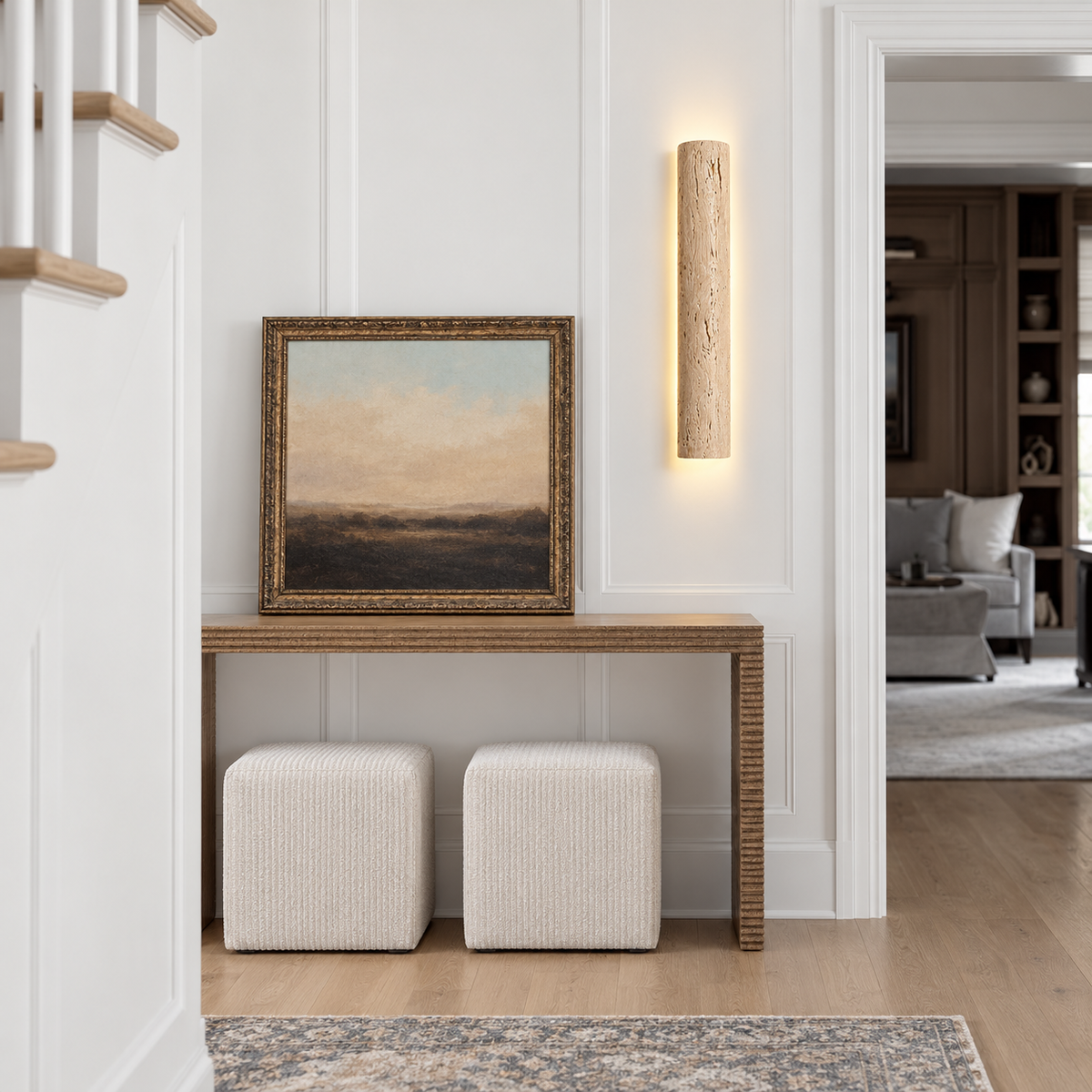 60 cm travertine wall sconce mounted beside artwork above an entryway console.