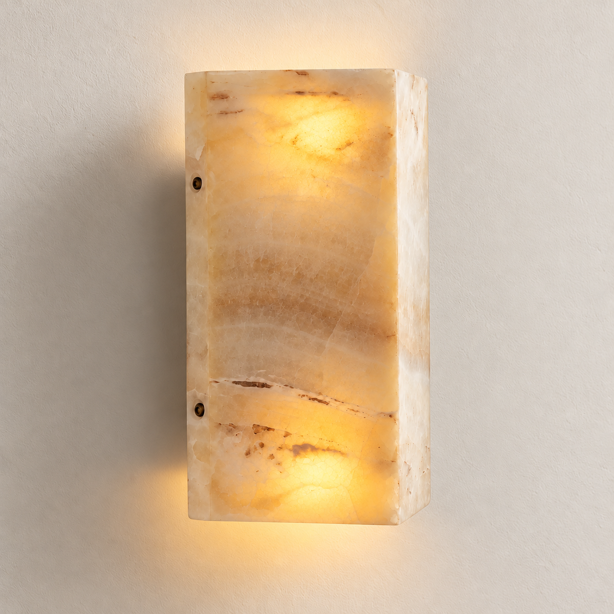 Honey onyx wall sconce illuminated at the top and bottom, revealing the stone’s natural banding.