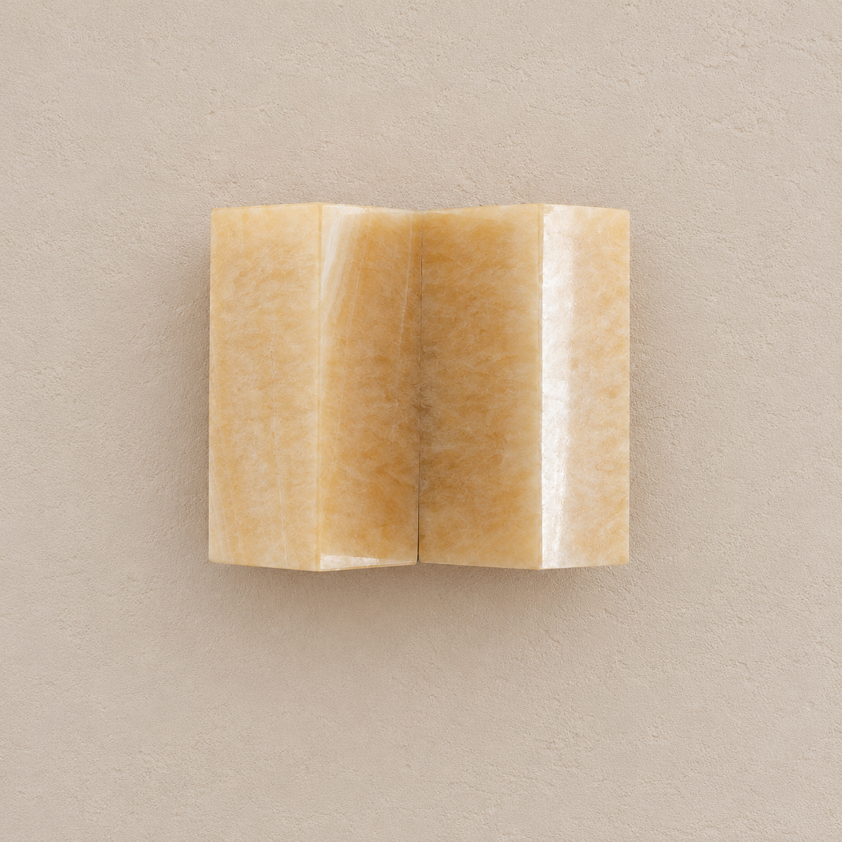 Front view of the CLMZUP onyx sconce showing both curved panels, unlit on pale beige.