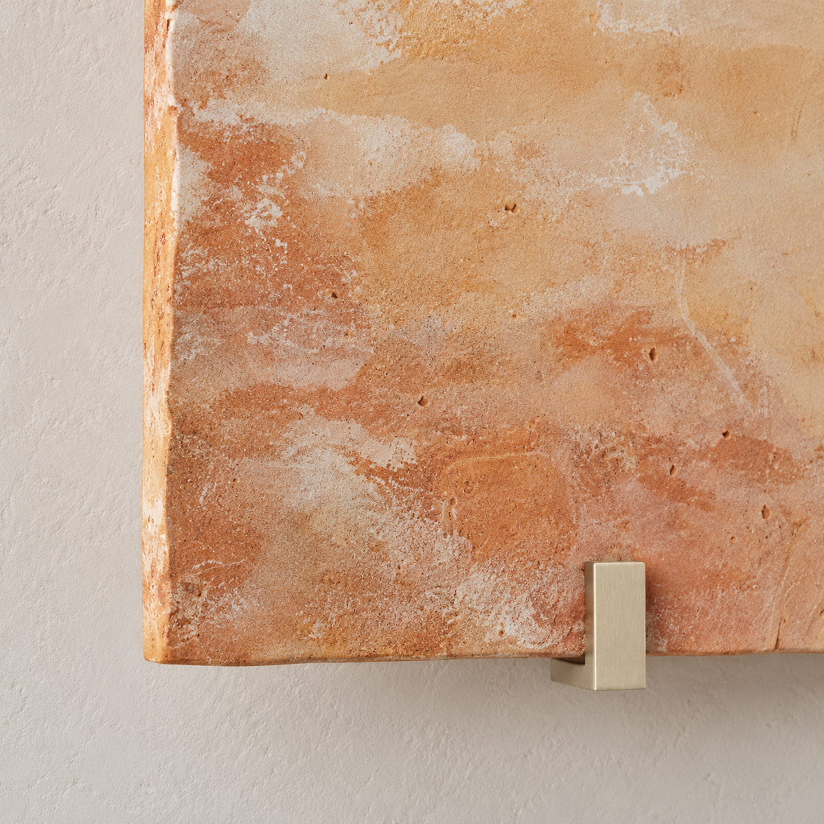 Close-up of veined orange onyx and a brass retaining clip on the Parefeuille Petite sconce.