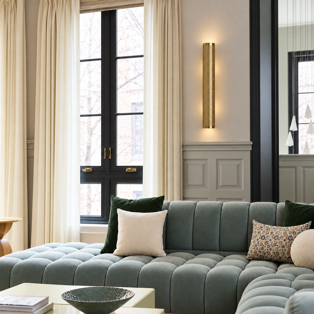 Perforated brass cylinder wall light mounted straight above a sofa.