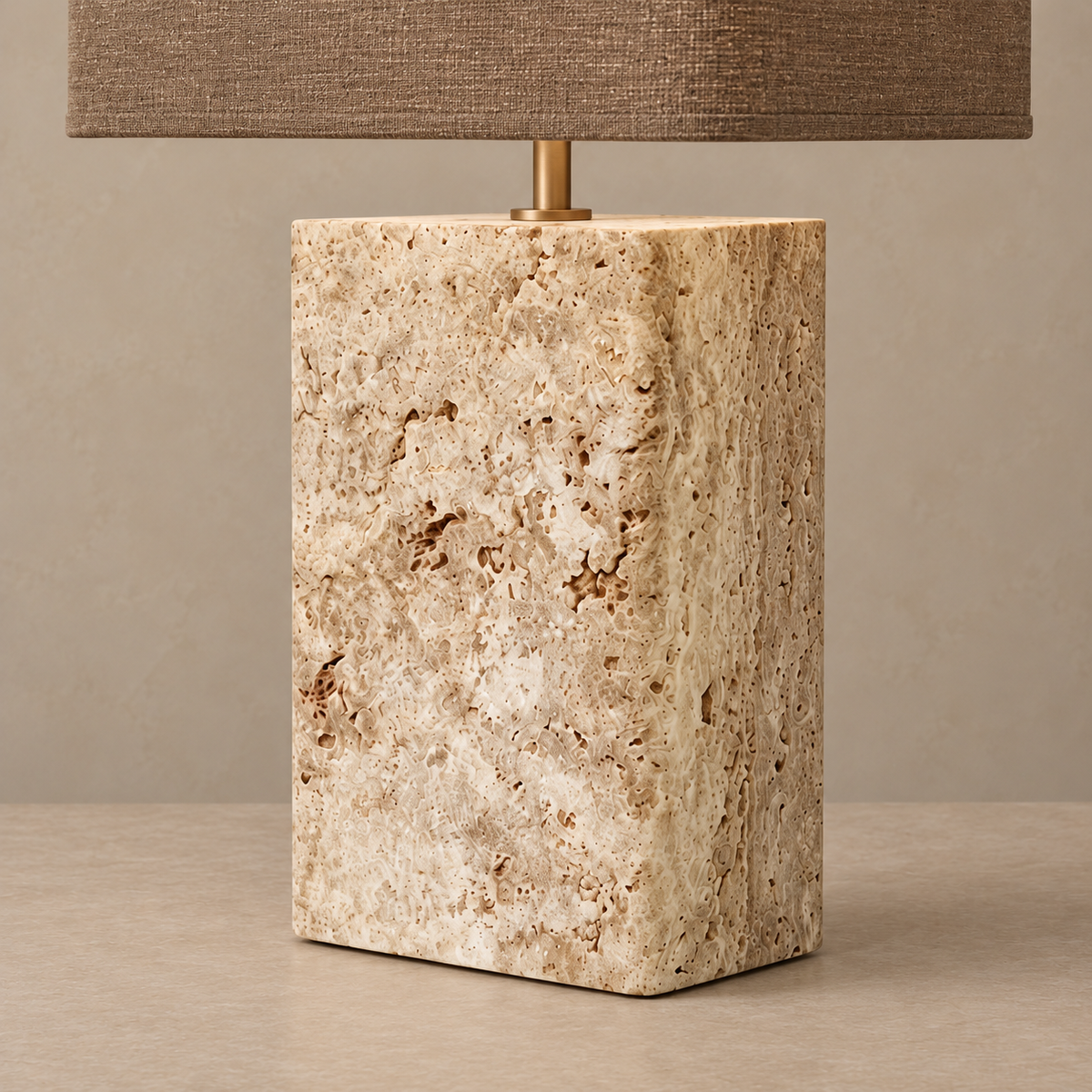 Close view of the travertine block’s natural pores and brass shade support.